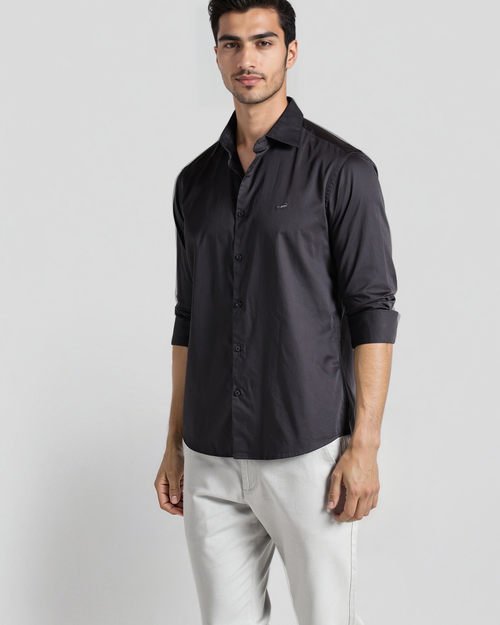 Man wearing a dark gray shirt and light gray pants on a white background