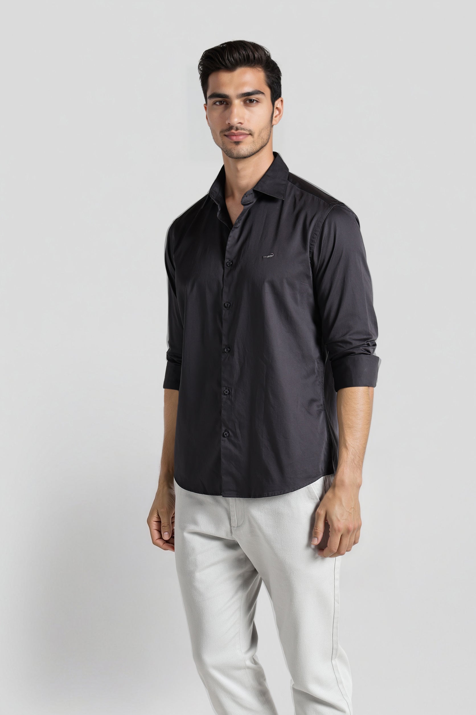 Man wearing a dark gray shirt and light gray pants on a white background