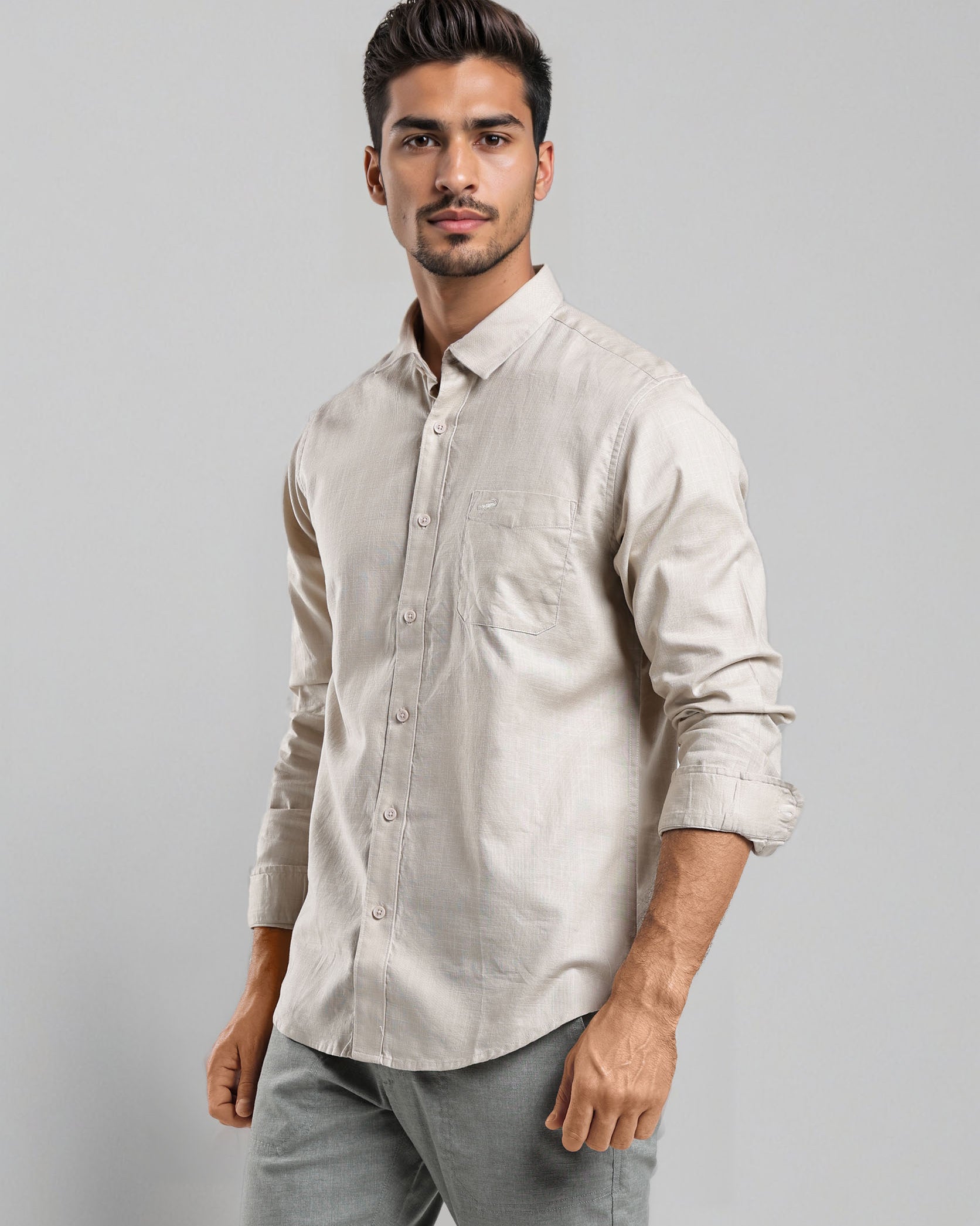 Man wearing a light-colored shirt and gray pants against a plain background