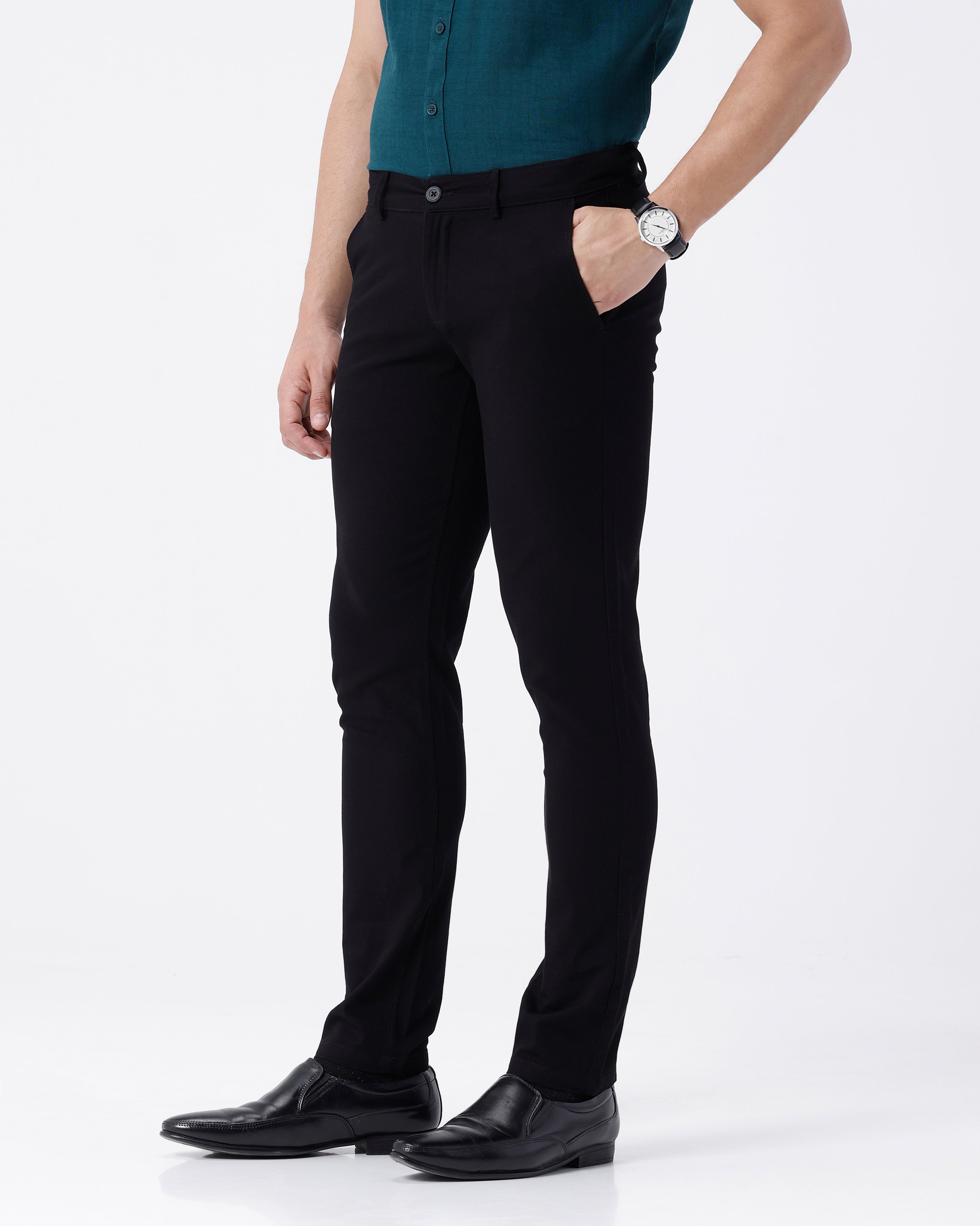 Woman wearing a black textured essential chinos in black on a light gray background