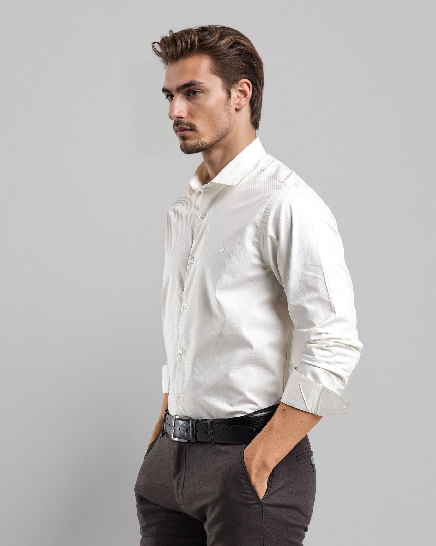 Man wearing a white dress shirt and dark pants against a gray background