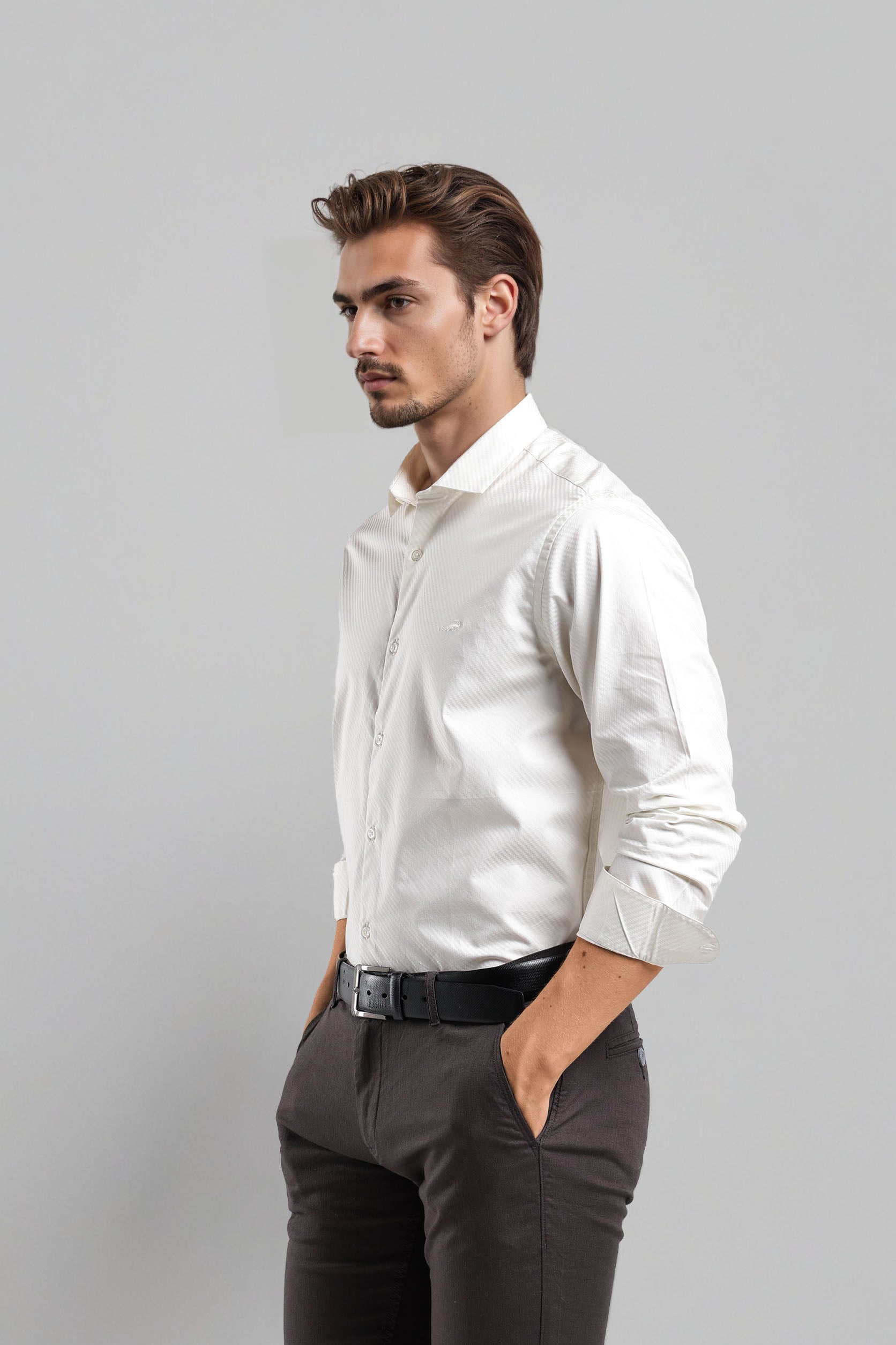 Man wearing a white dress shirt and dark pants against a gray background