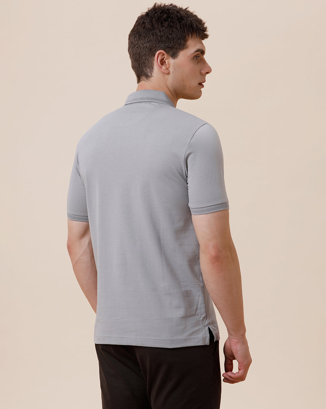 Man wearing a solid half sleeve casual polo t shirt on a light gray background