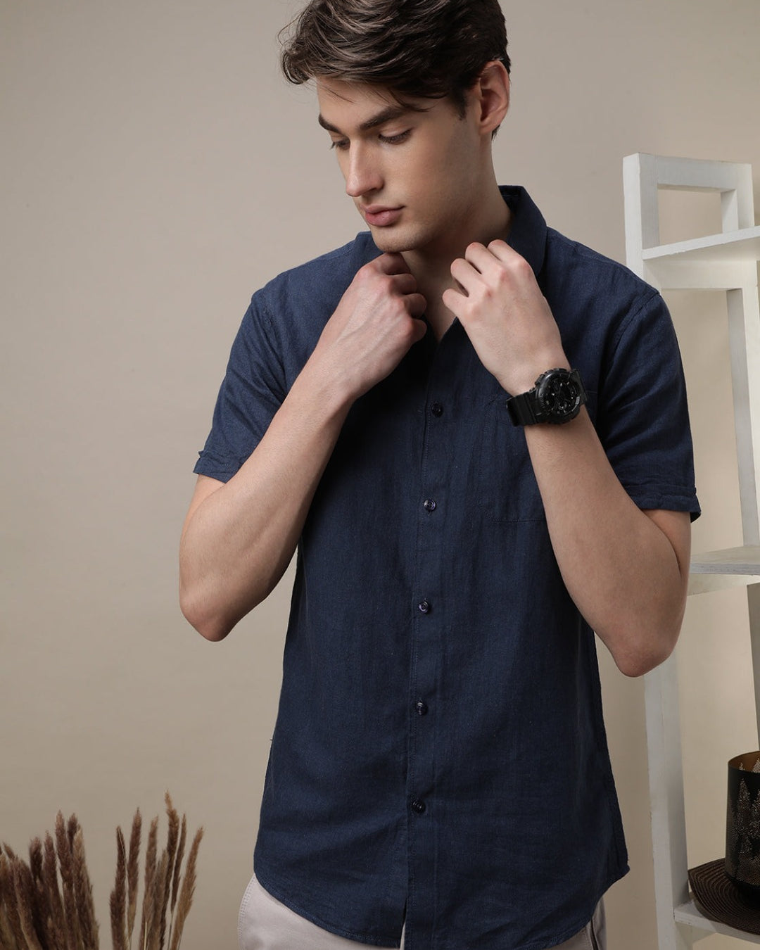 Man wearing a navy navy solid half sleeve linen shirt on a light gray background