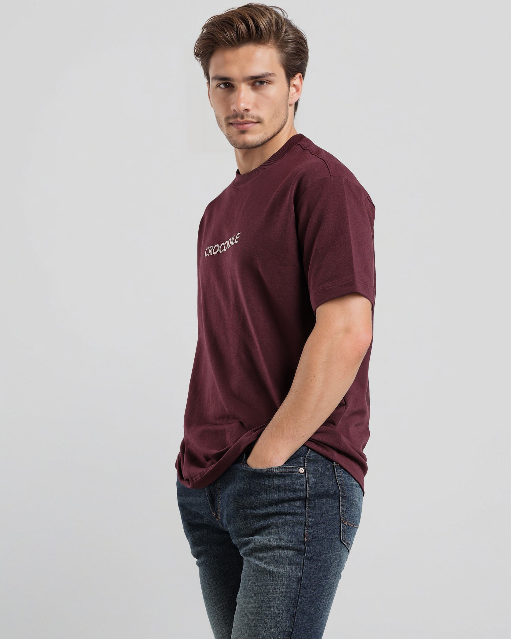 Man wearing a maroon t-shirt with a logo on a light gray background