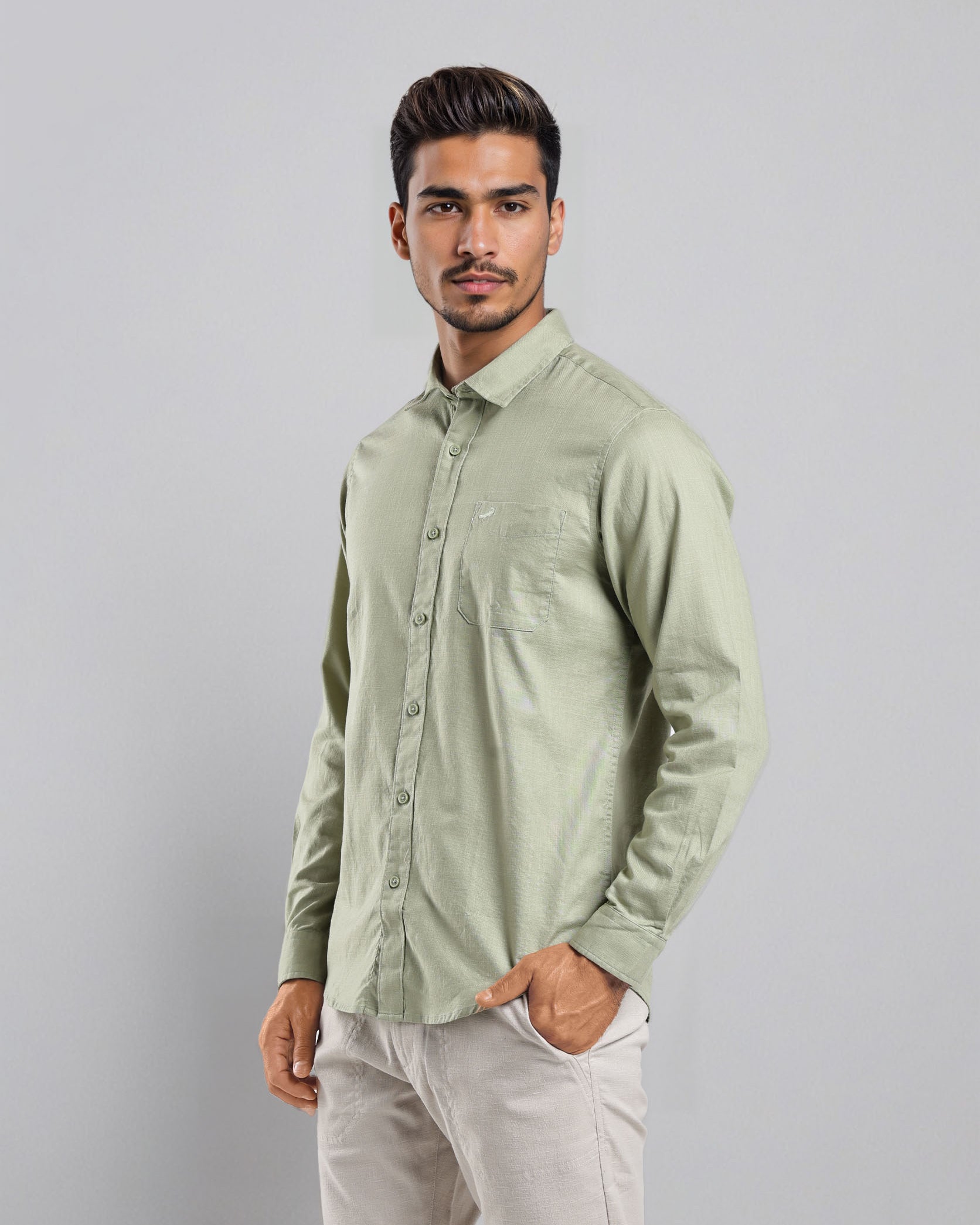 Man wearing a light green shirt and white pants against a gray background