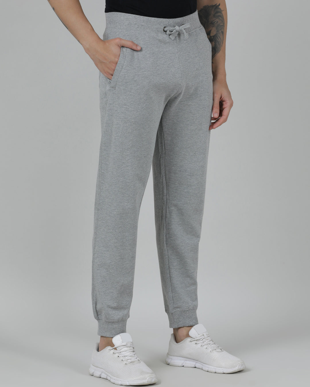 Person wearing gray sweatpants and white sneakers on a plain background