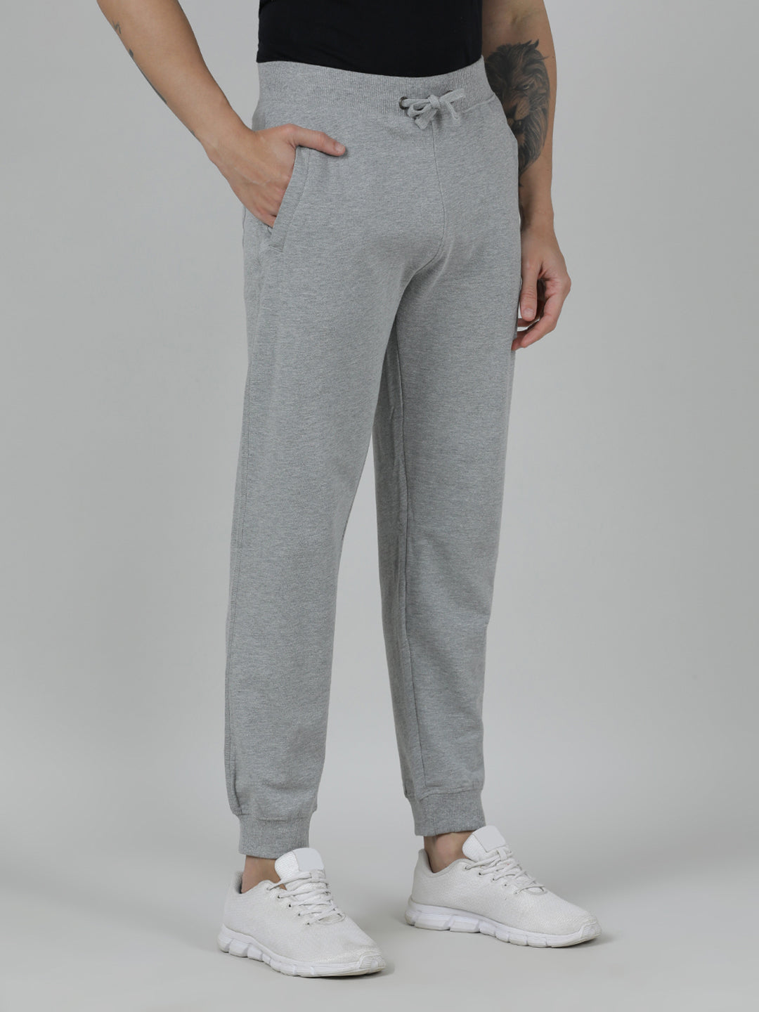 Person wearing gray sweatpants and white sneakers on a plain background