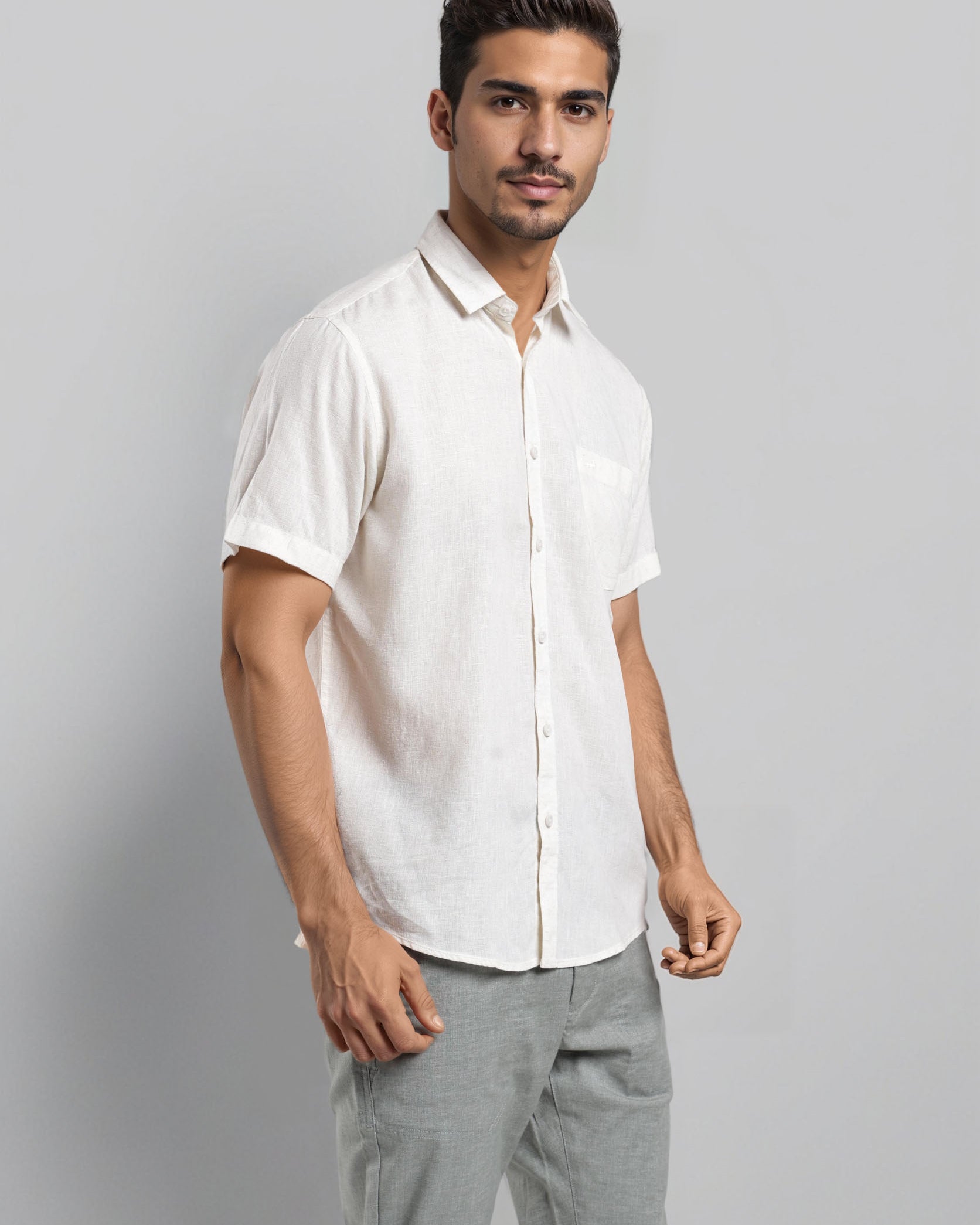 Man wearing a white shirt and gray pants against a plain background