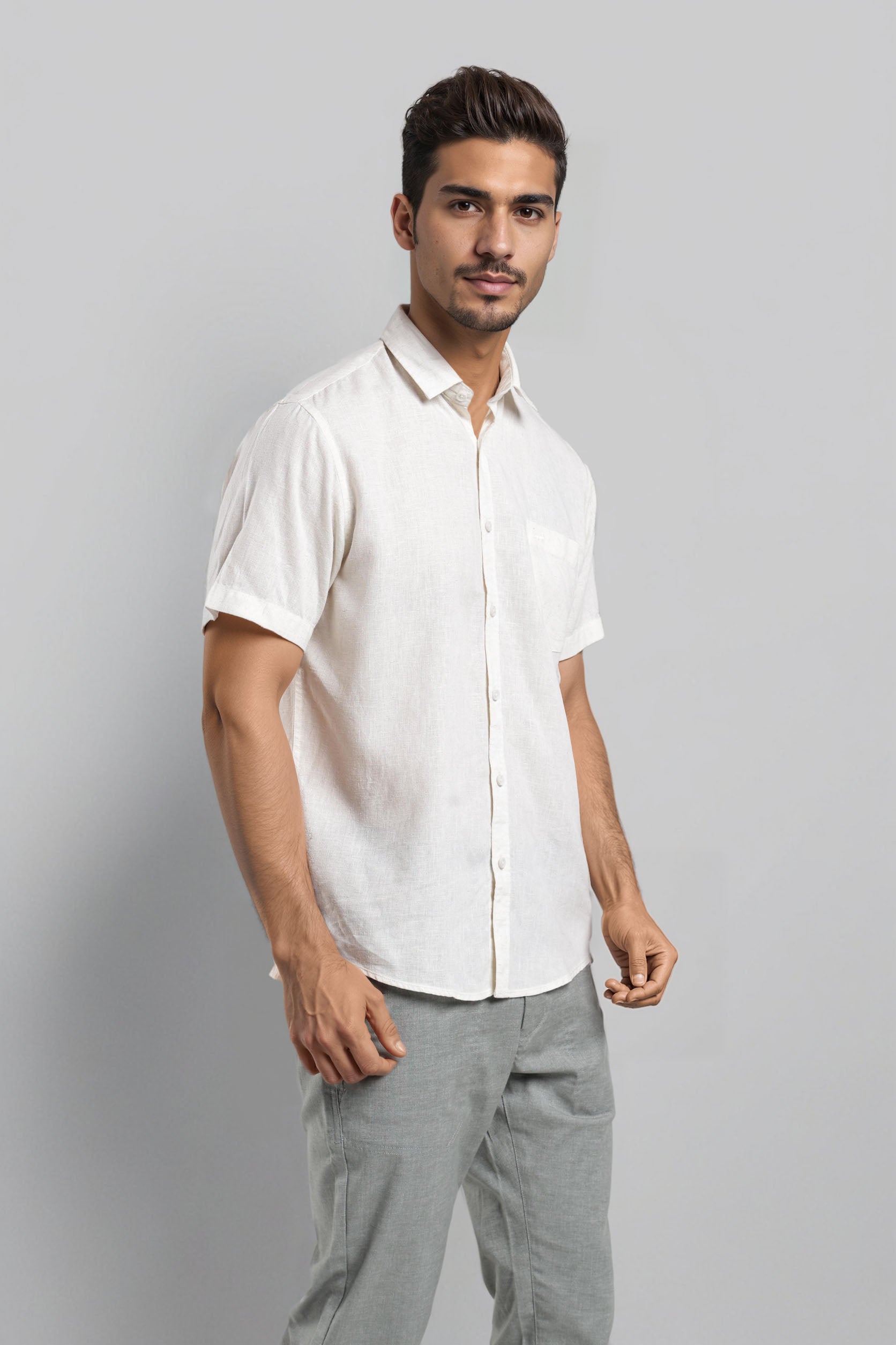 Man wearing a white shirt and gray pants against a plain background