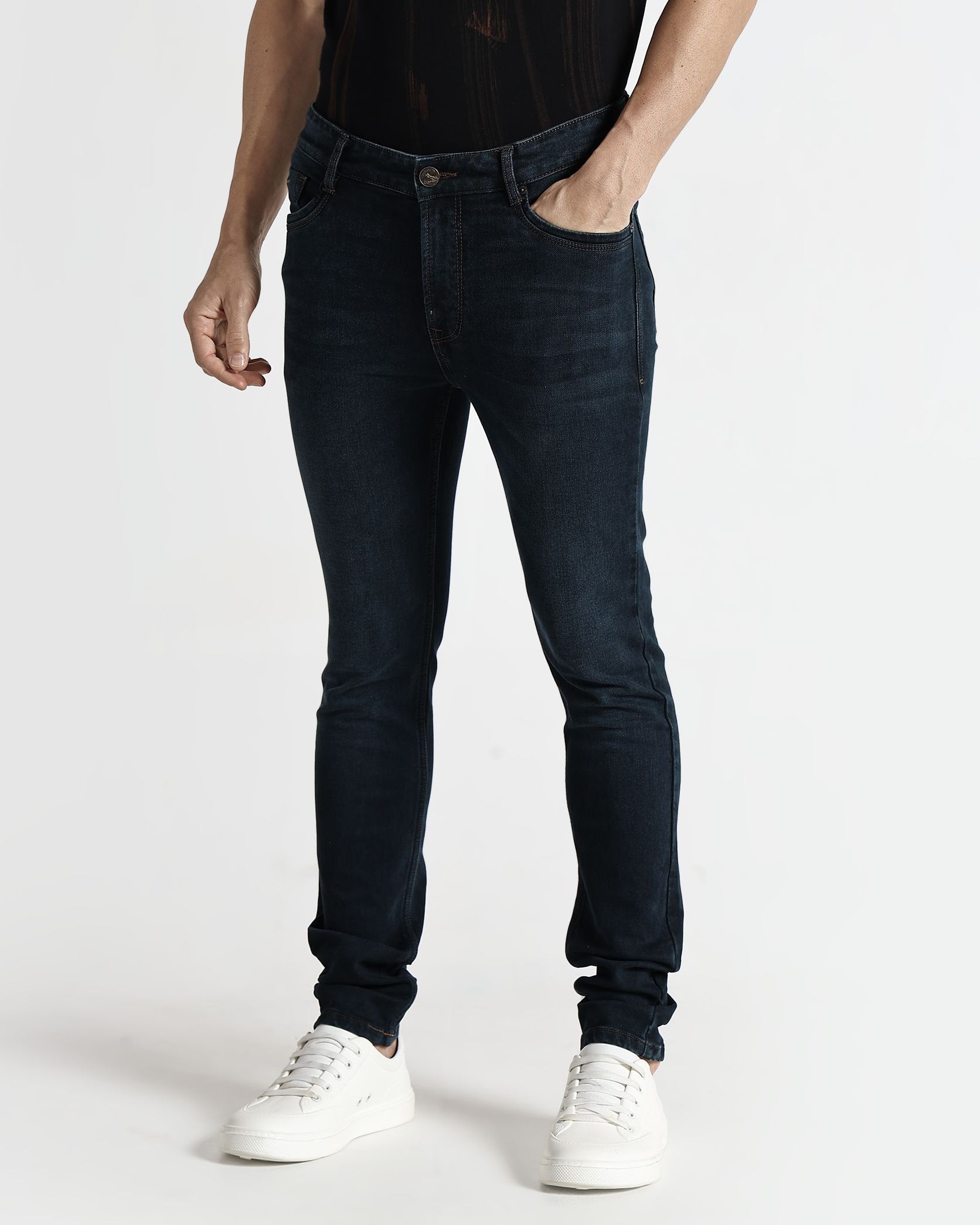Person wearing dark jeans and white sneakers on a white background