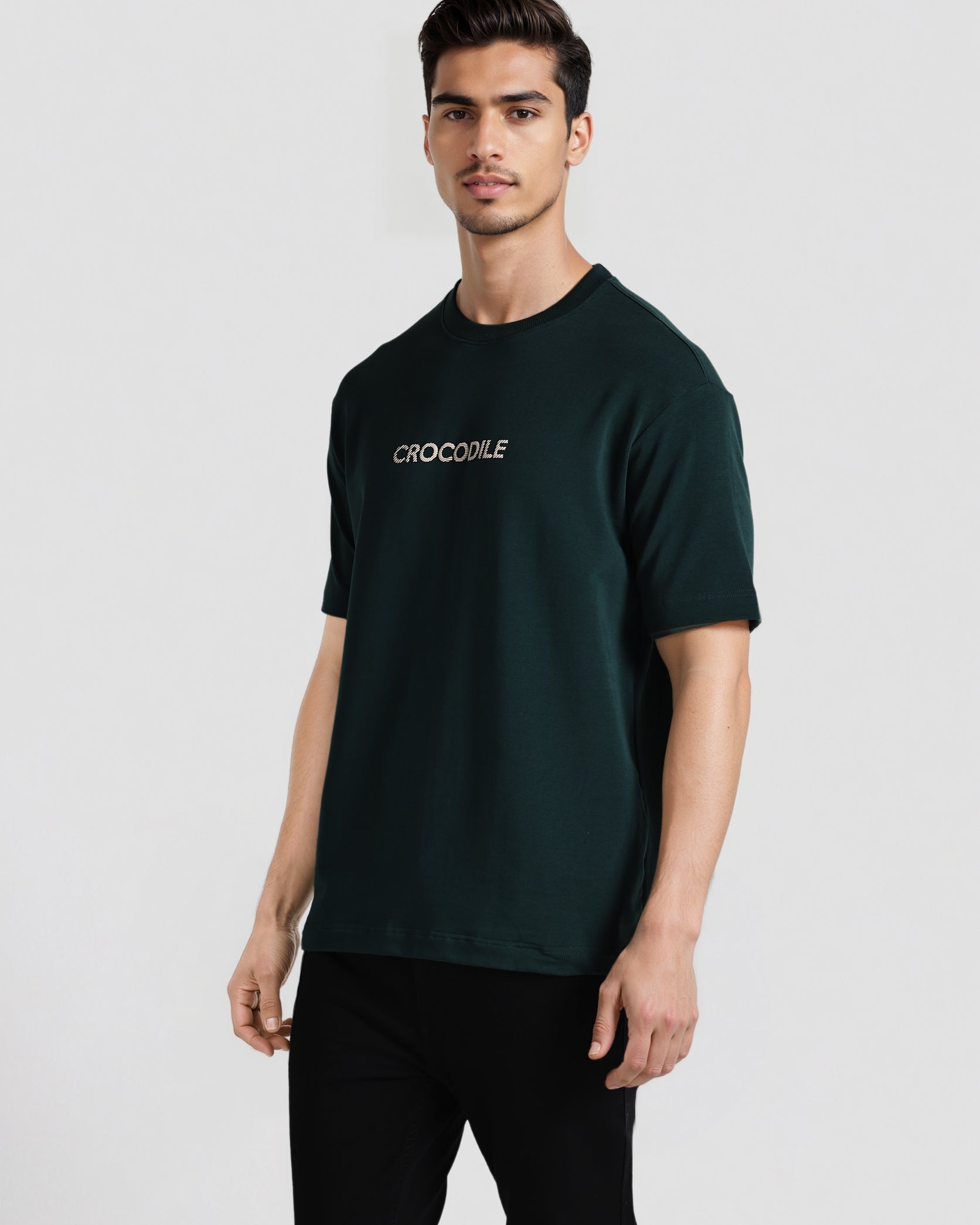 Man wearing a dark green t-shirt with 'Crocodile' logo on a white background