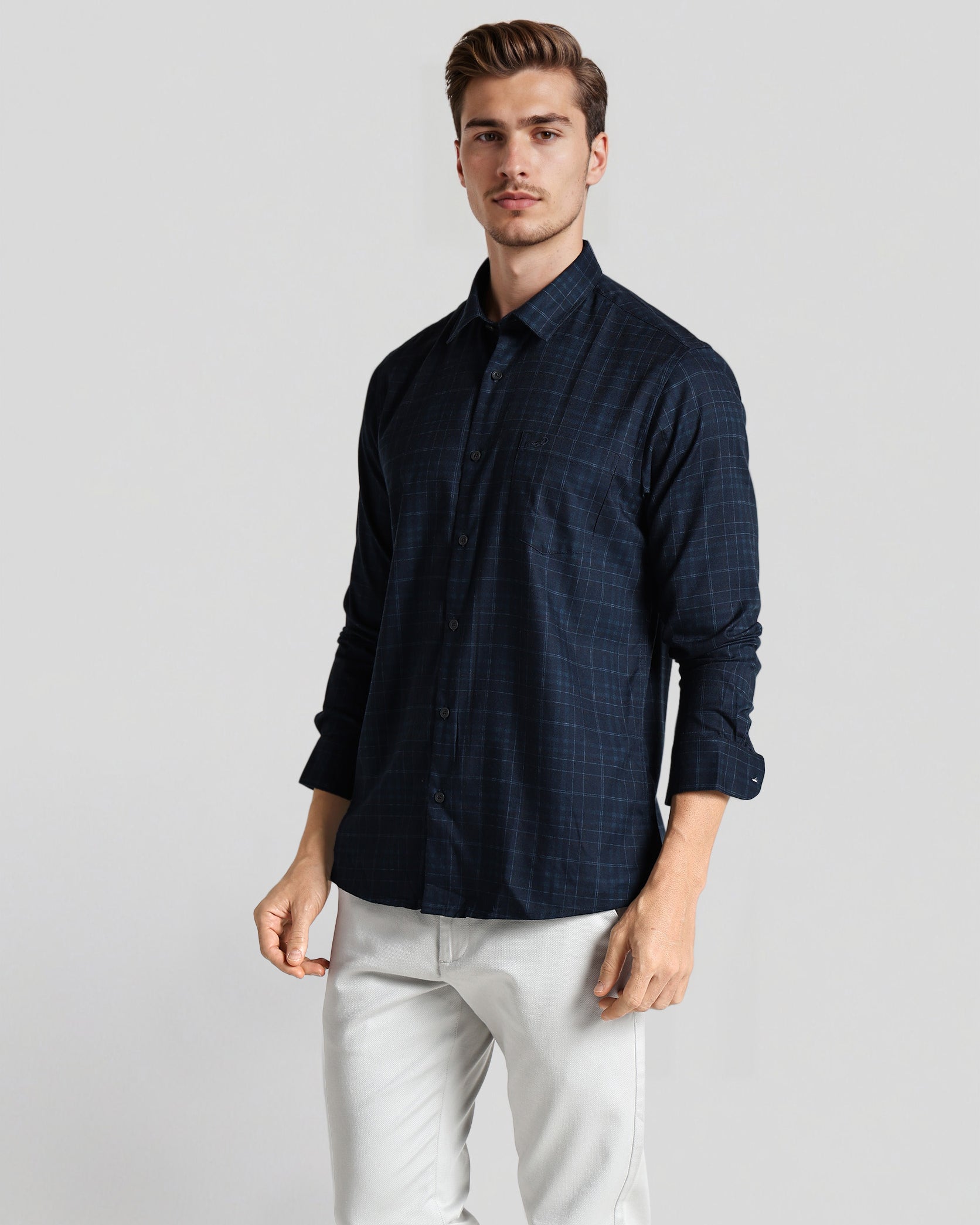 Man wearing a dark blue shirt and light-colored pants on a plain background