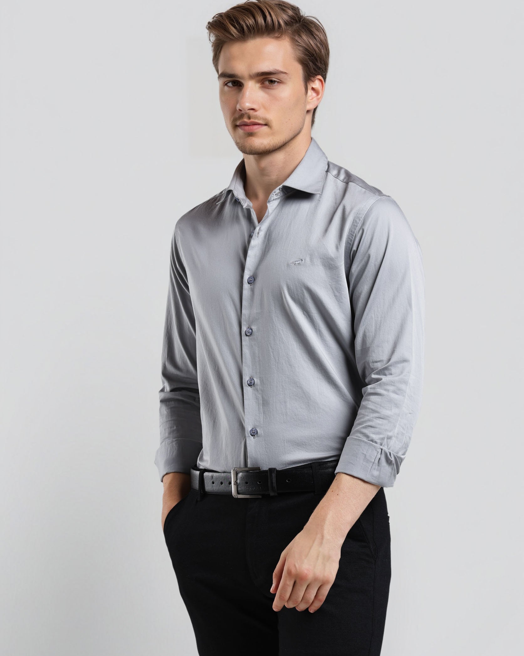 Man wearing a light gray dress shirt and black pants on a white background