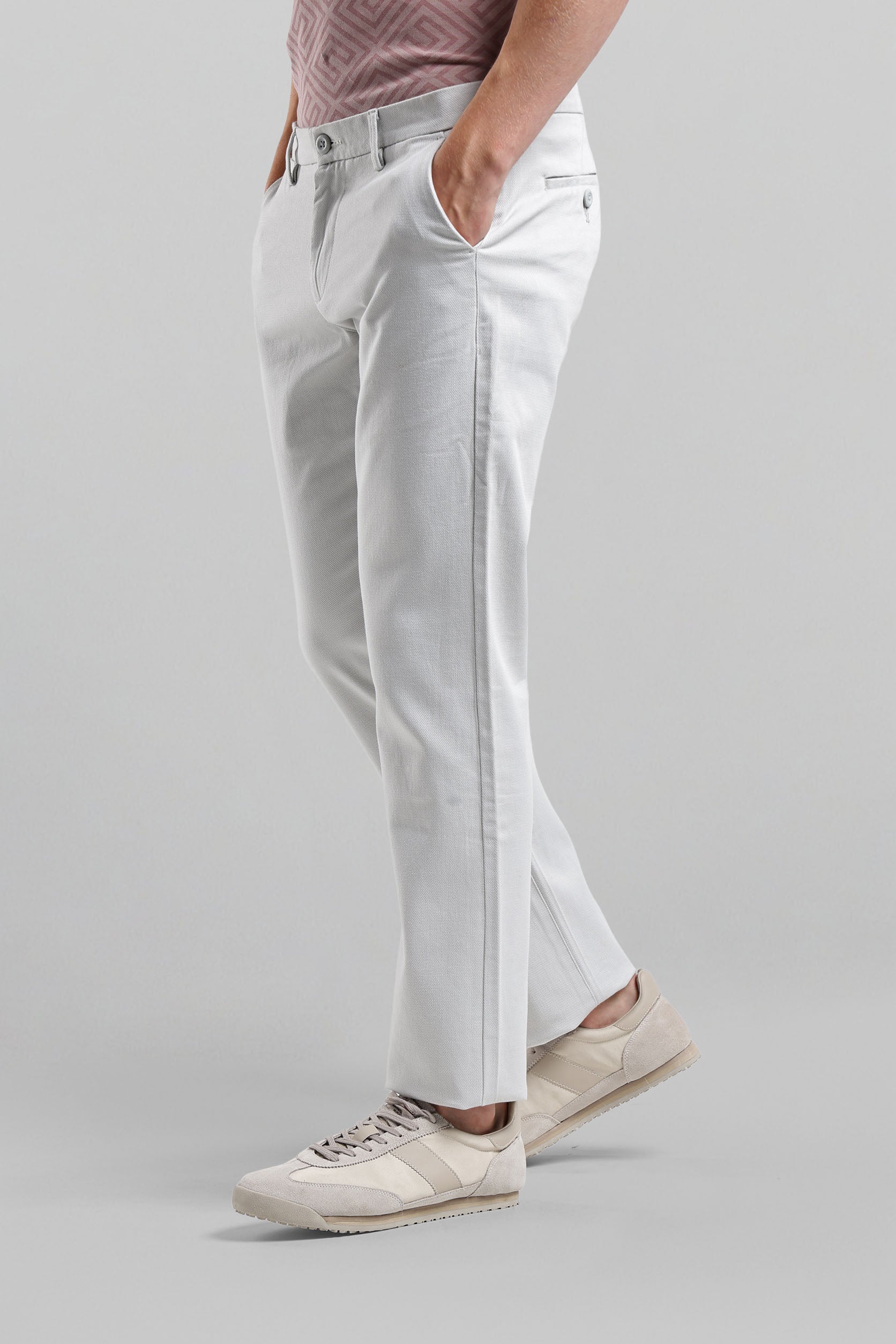 Person wearing light gray pants and beige sneakers on a plain background