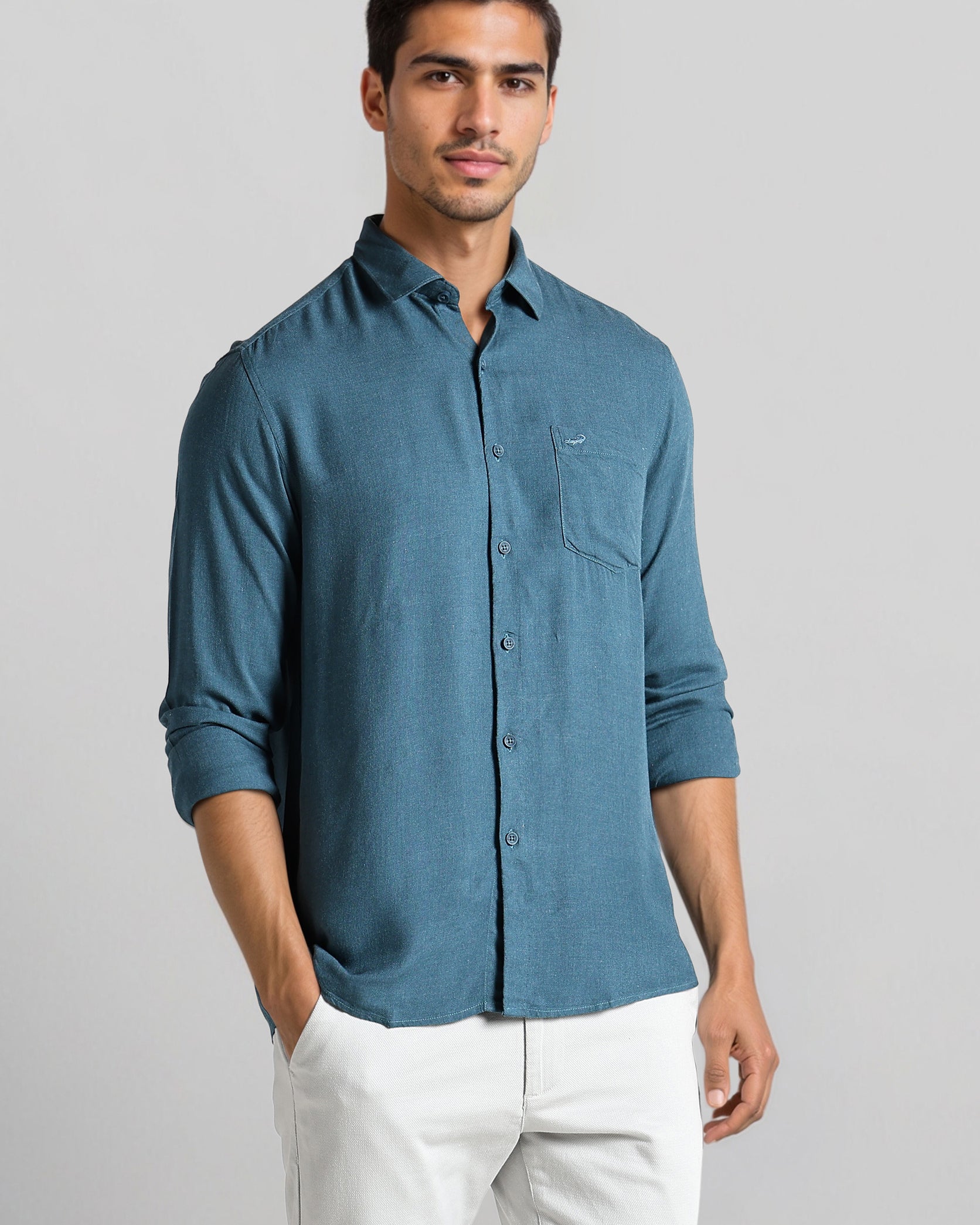 Man wearing a blue shirt and white pants on a gray background