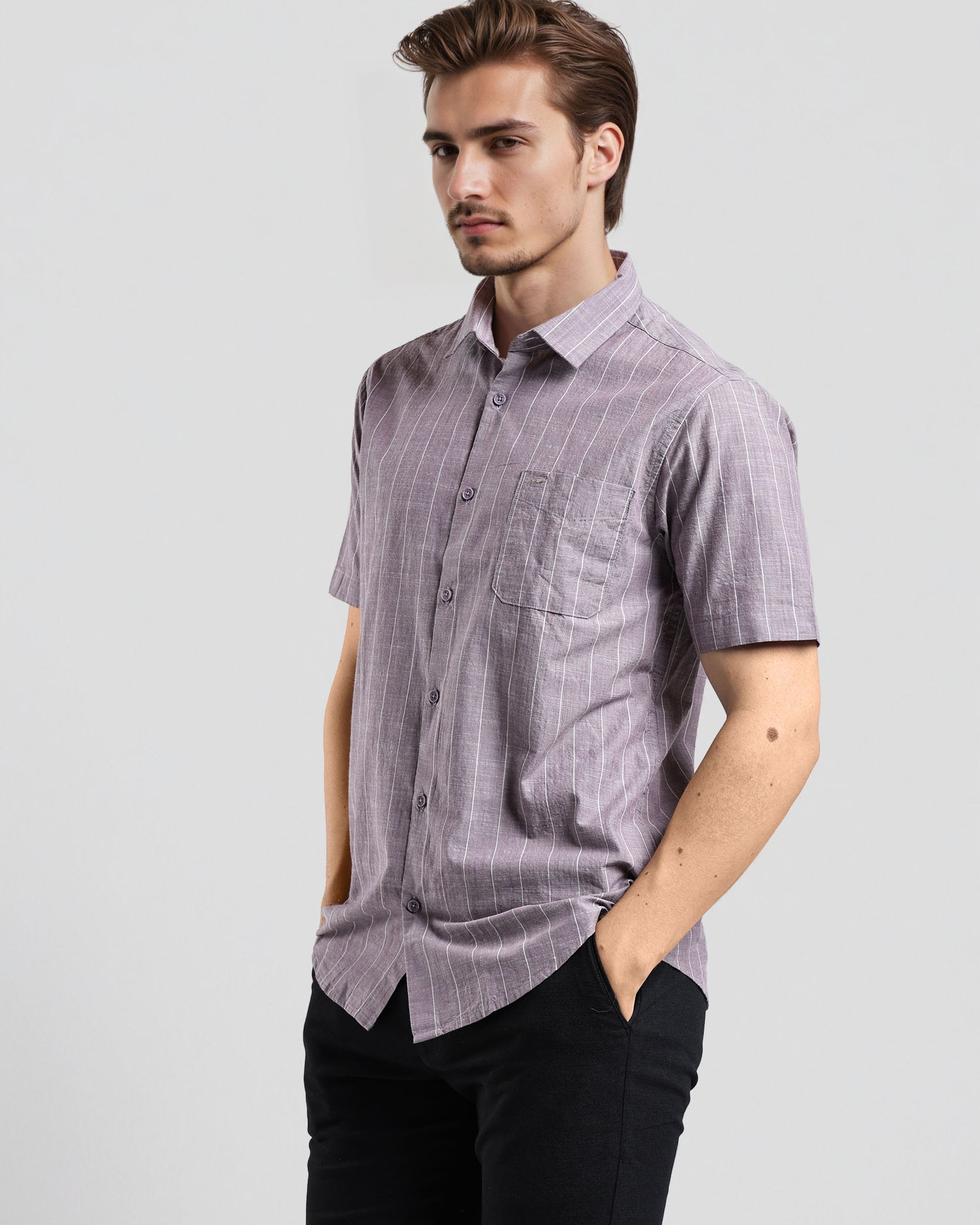 Man wearing a short-sleeve checkered shirt and black pants on a light gray background