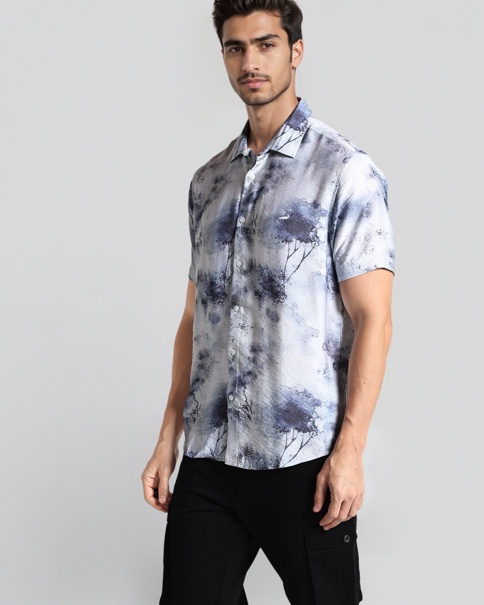 Man wearing a short-sleeve, patterned shirt against a plain background