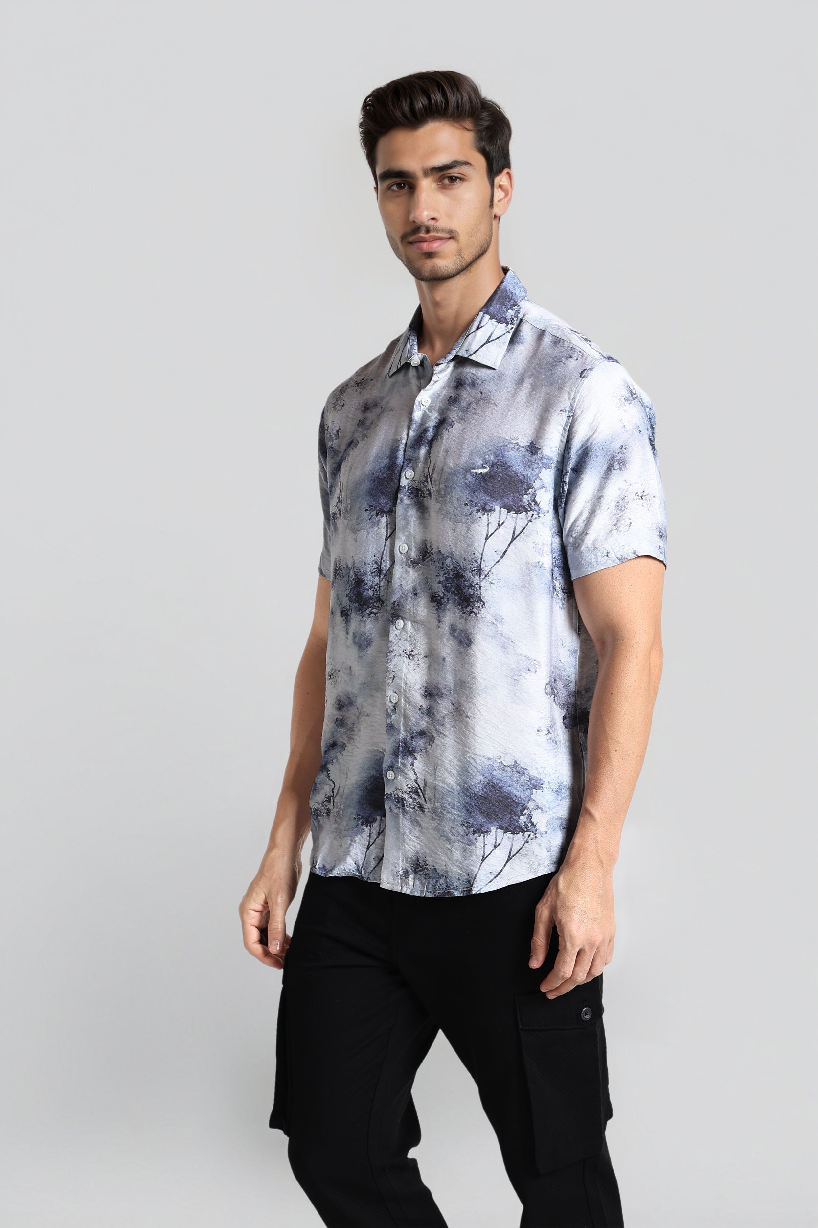 Man wearing a short-sleeve, patterned shirt against a plain background