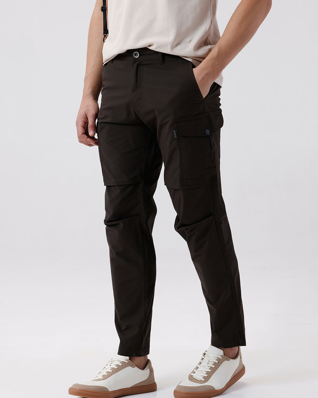 Man wearing a grey utility trekflex cargo pant in dark grey on a light gray background
