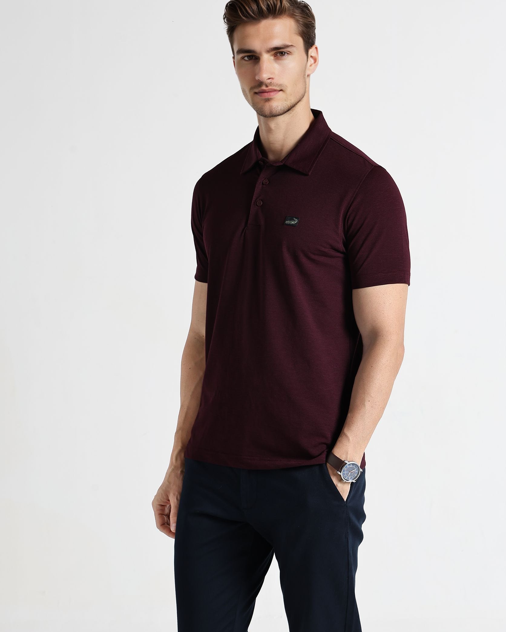 Man wearing a maroon polo shirt with a logo on a white background