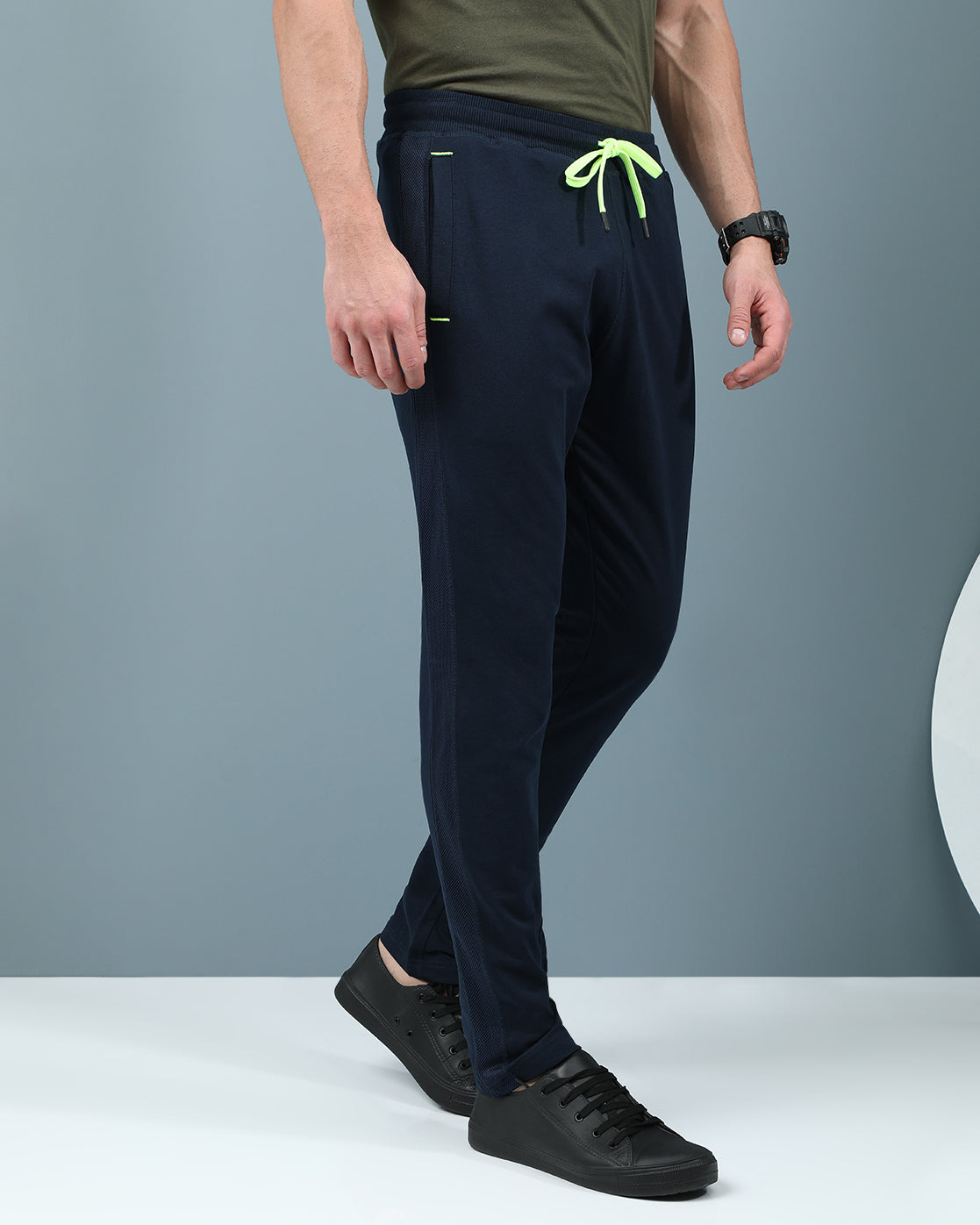 Man wearing a navy slim fit track pants in flexible navy on a light gray background