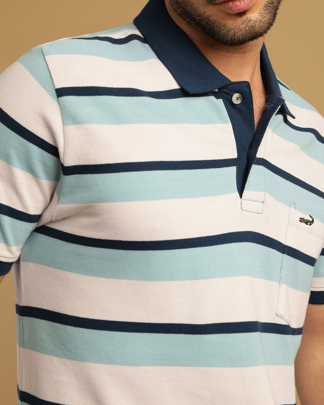 Man wearing a white blue and white striped polo t shirt with casual styling on a gray background