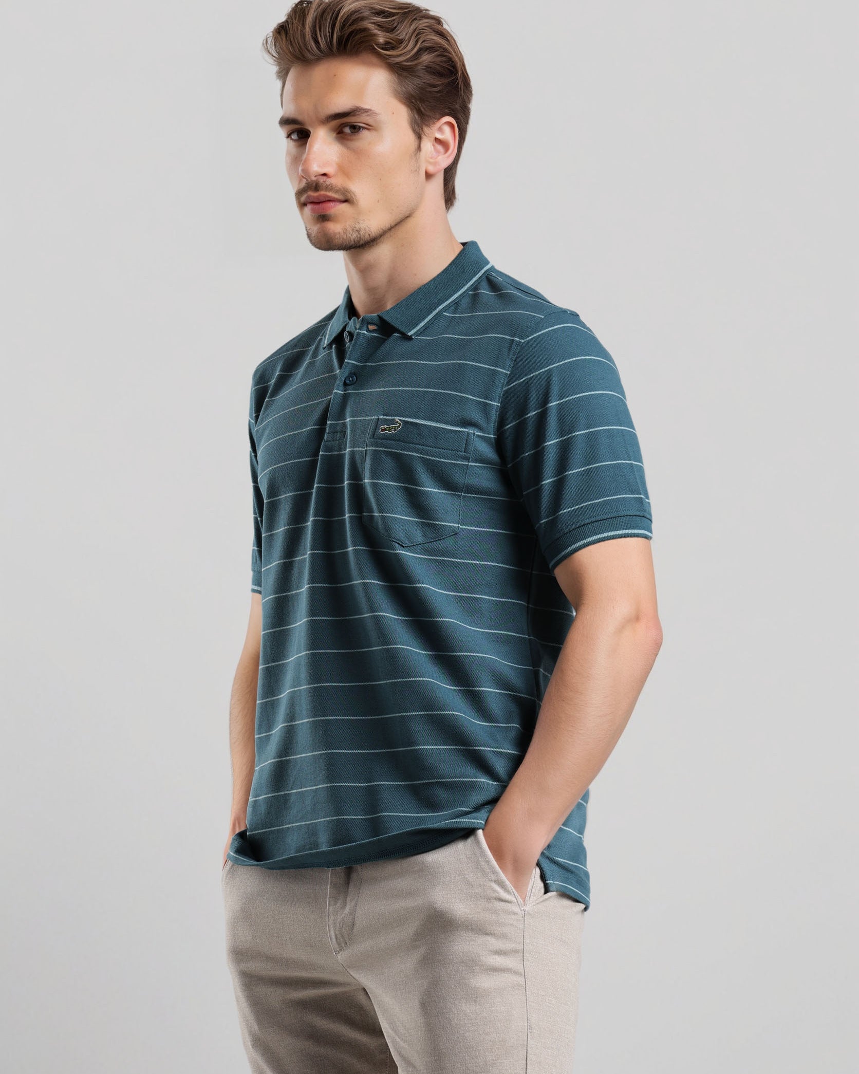 Man wearing a blue striped polo shirt and beige pants against a light gray background