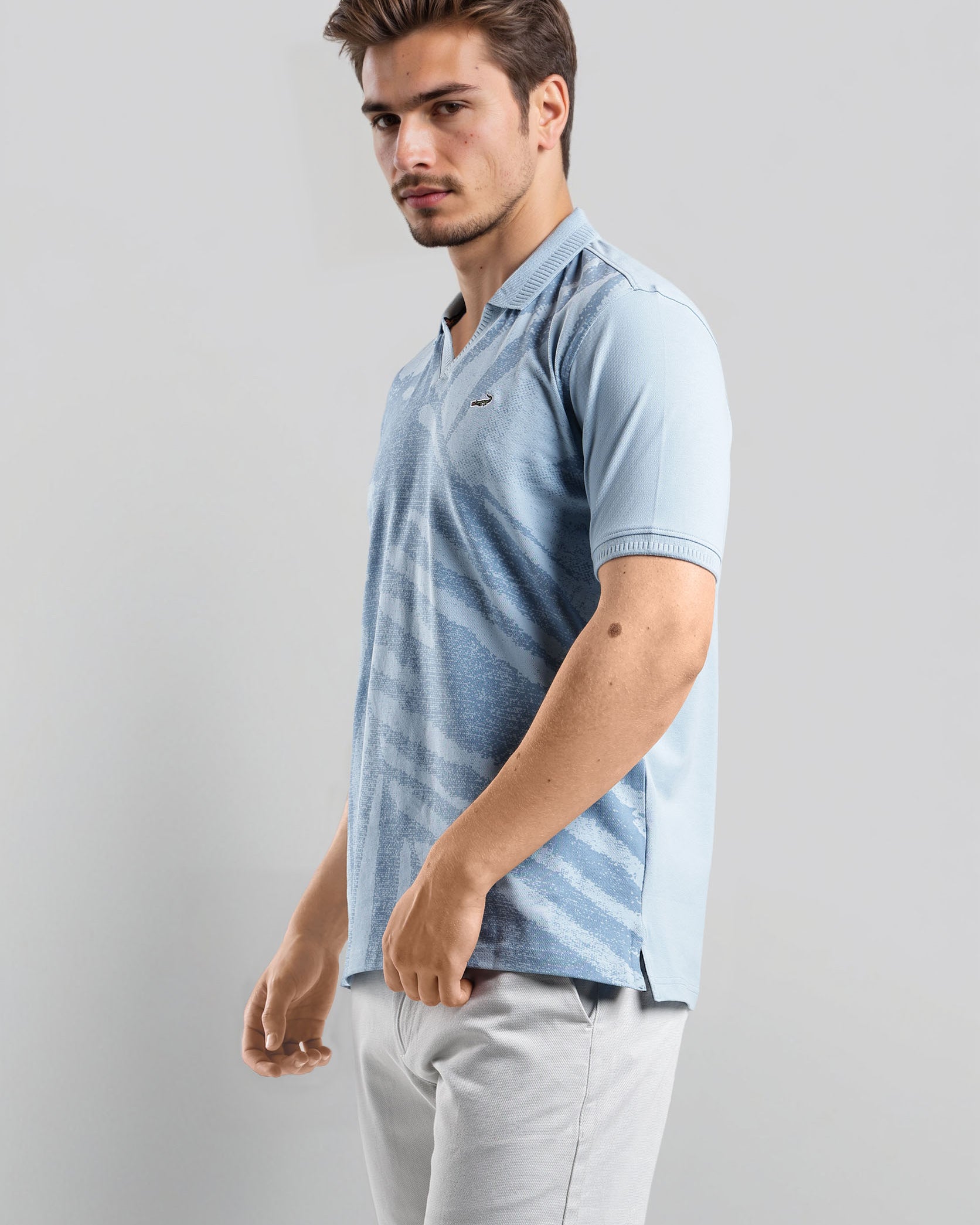 Man wearing a light blue striped polo shirt against a gray background