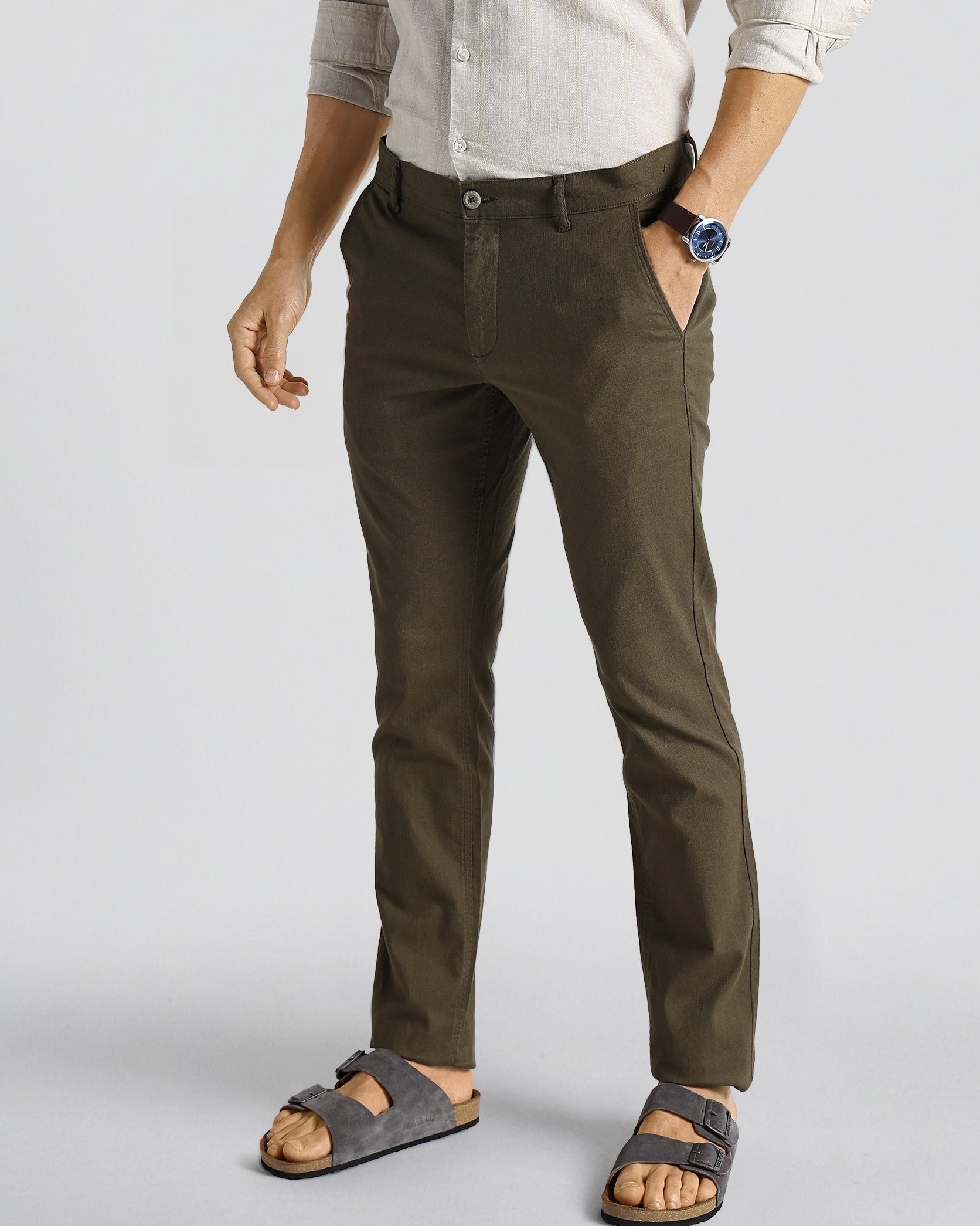 Person wearing olive green pants and sandals on a light gray background