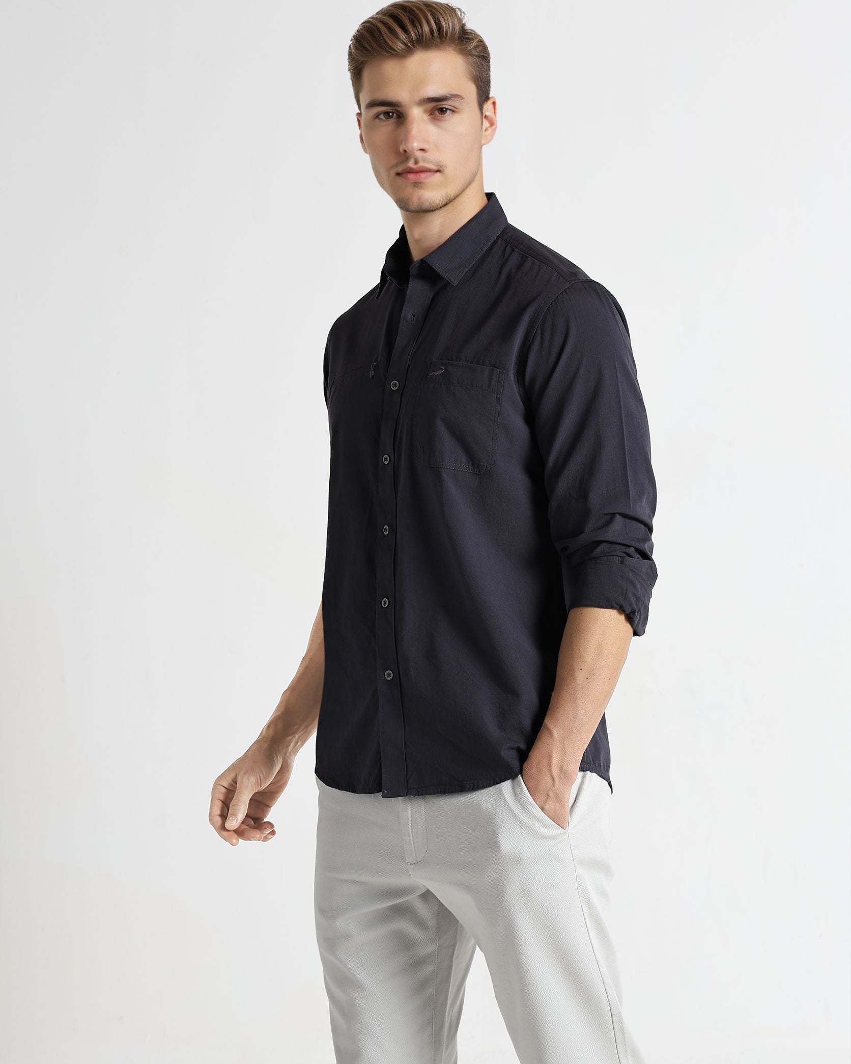 Man wearing a dark blue shirt and white pants on a white background