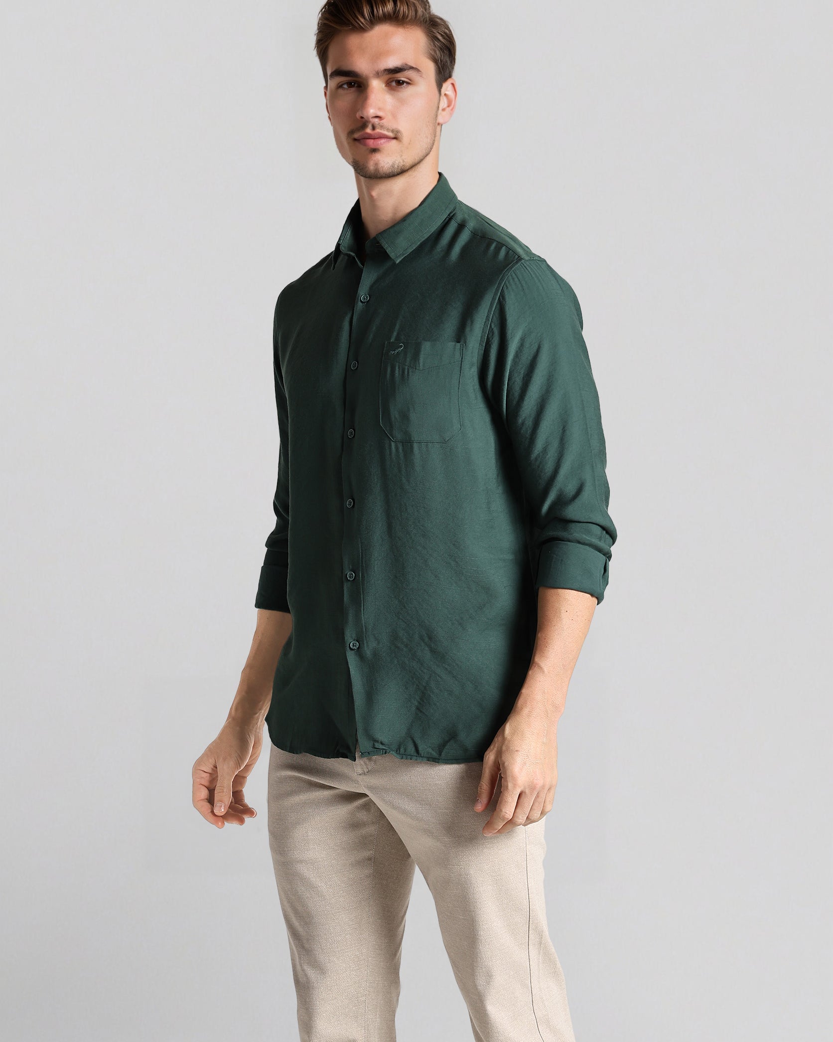 Man wearing a green shirt and beige pants on a gray background