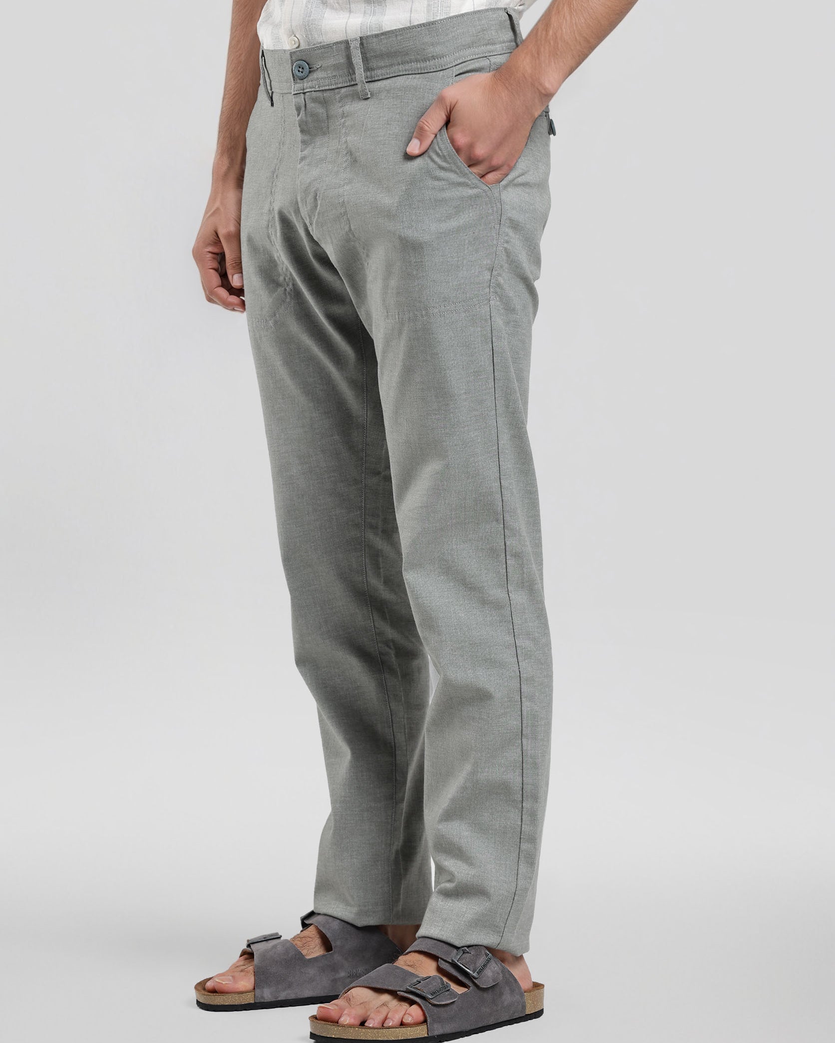 Person wearing gray pants and sandals on a plain background