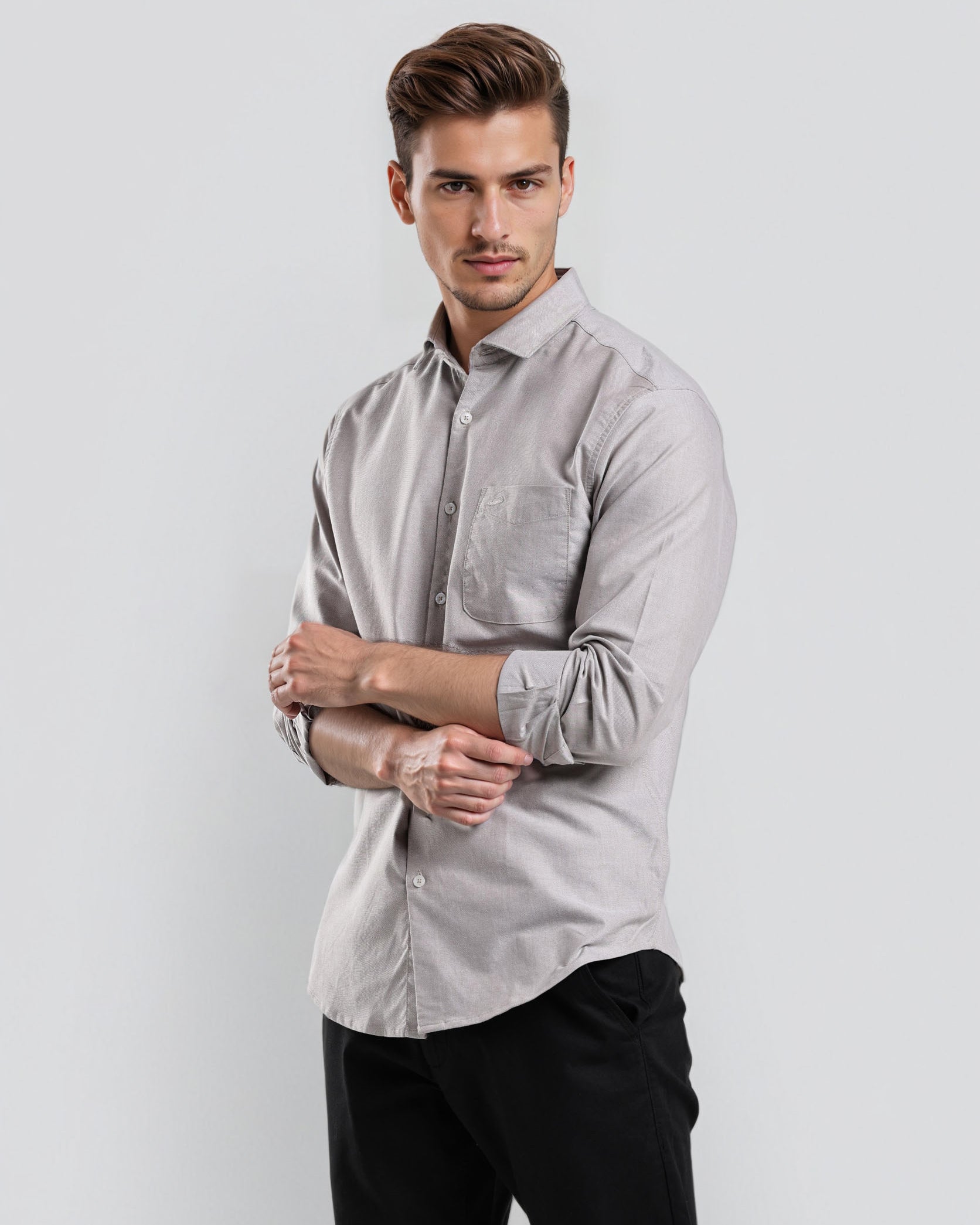 Man wearing a light gray button-up shirt and black pants on a white background