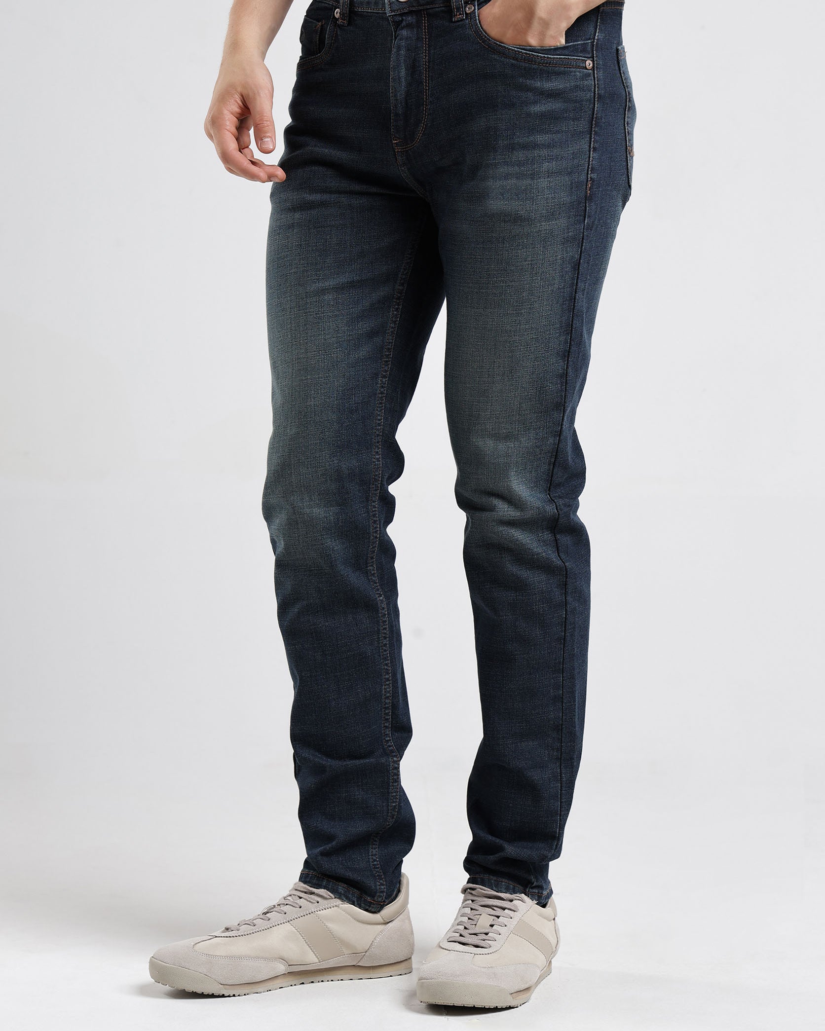 Person wearing dark blue jeans on a white background