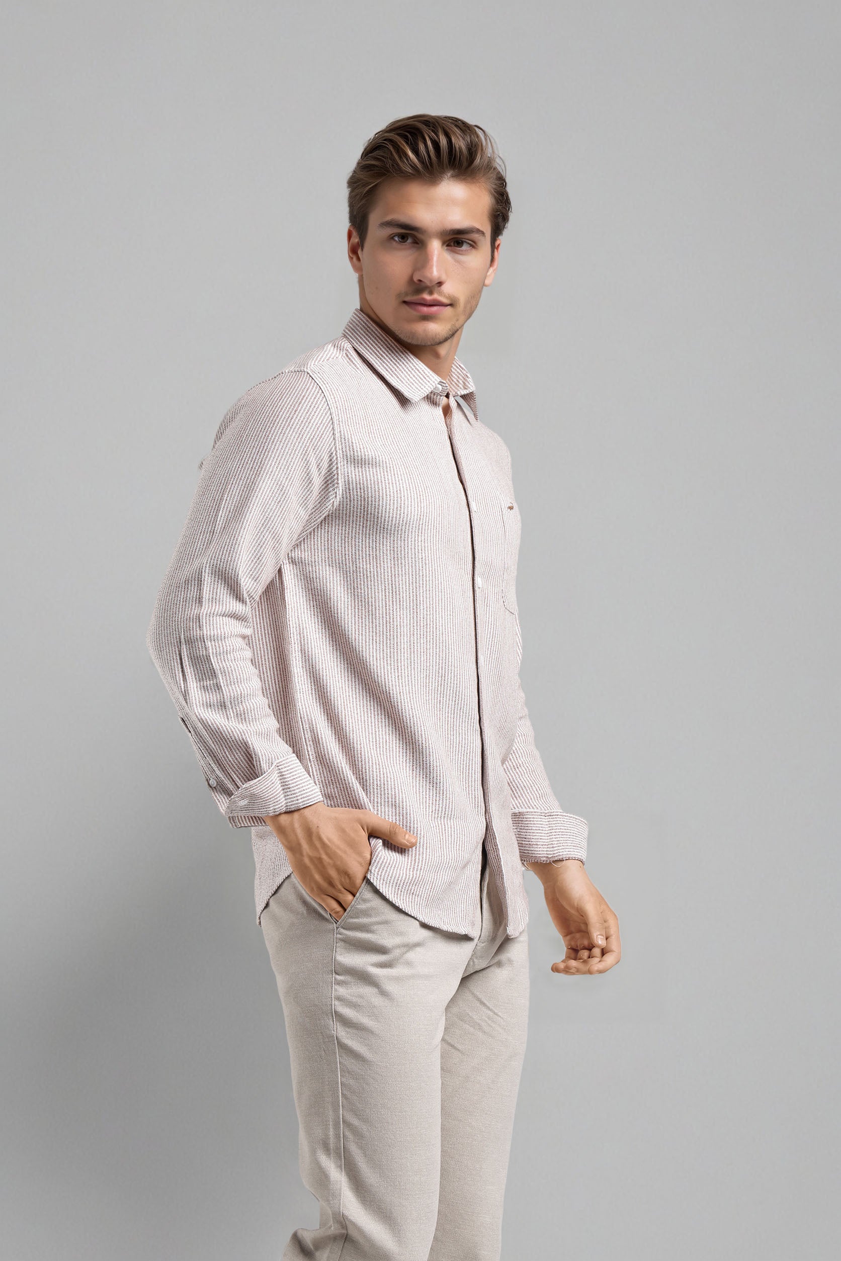 Man wearing a light pink shirt and beige pants against a gray background