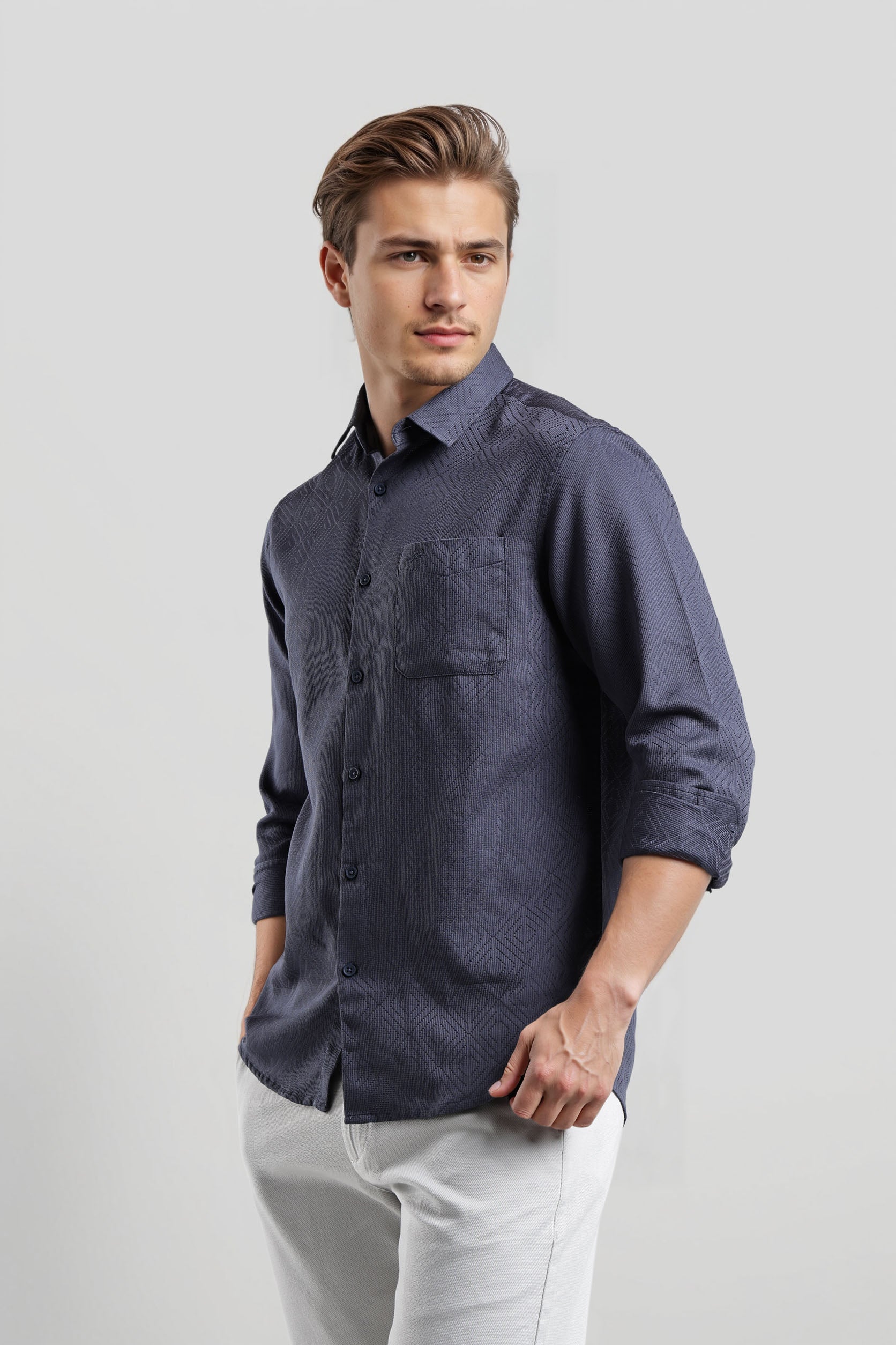 Man wearing a dark blue button-up shirt and light gray pants on a white background