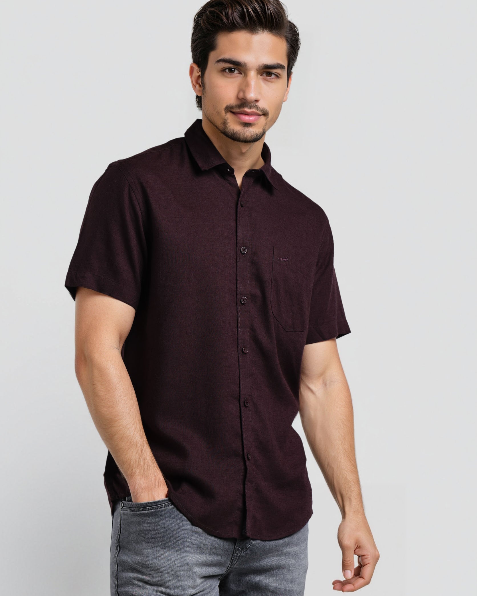 Man wearing a dark brown button-up shirt and gray pants on a white background