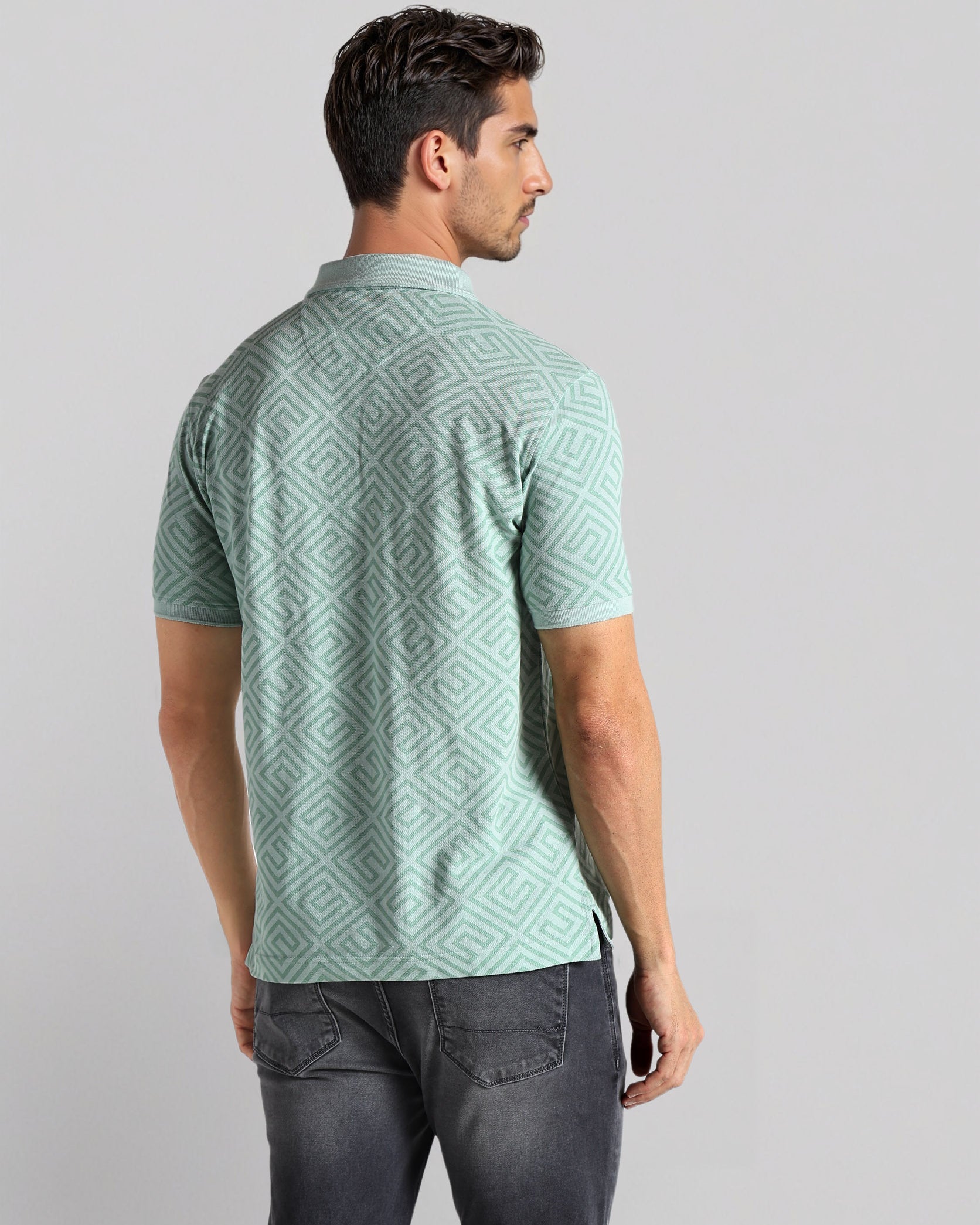 Man wearing a green patterned shirt on a light gray background