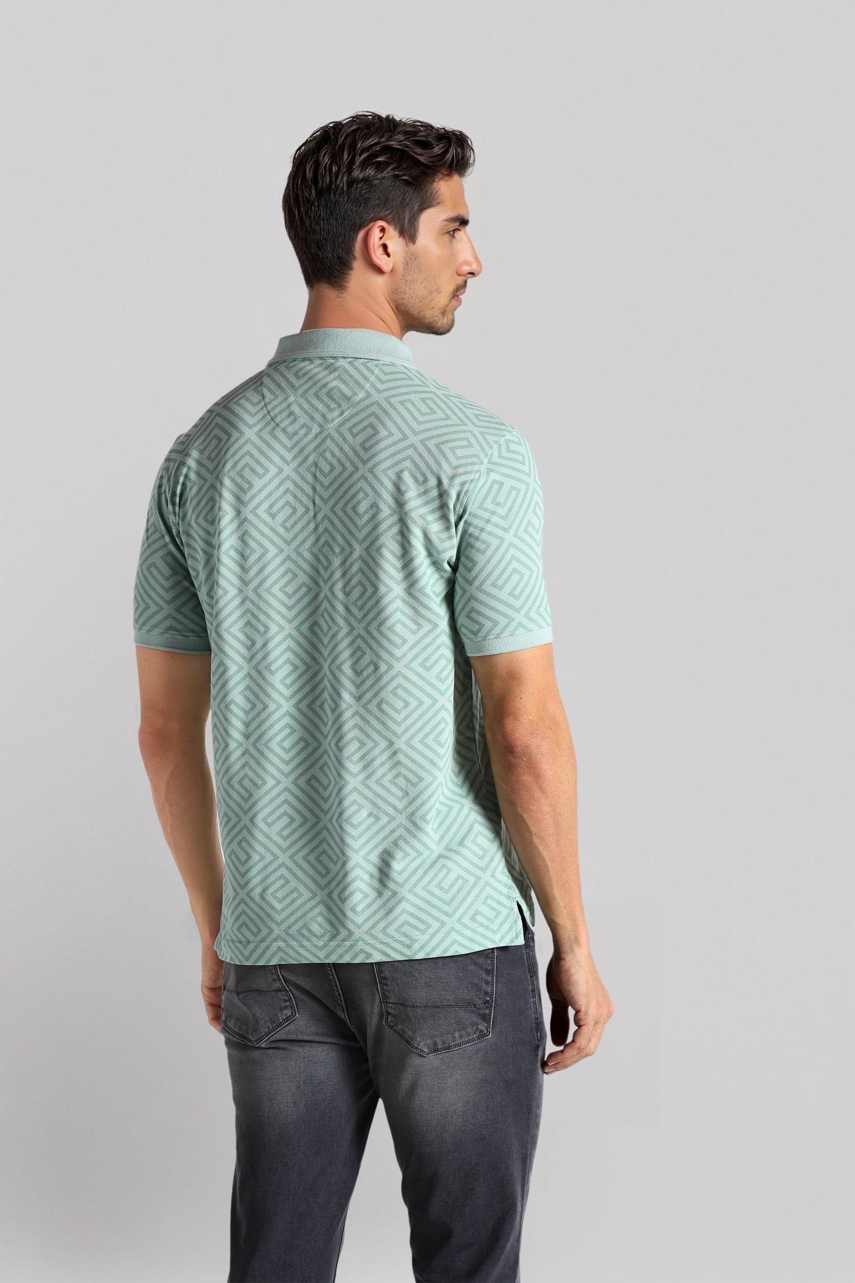 Man wearing a green patterned shirt on a light gray background