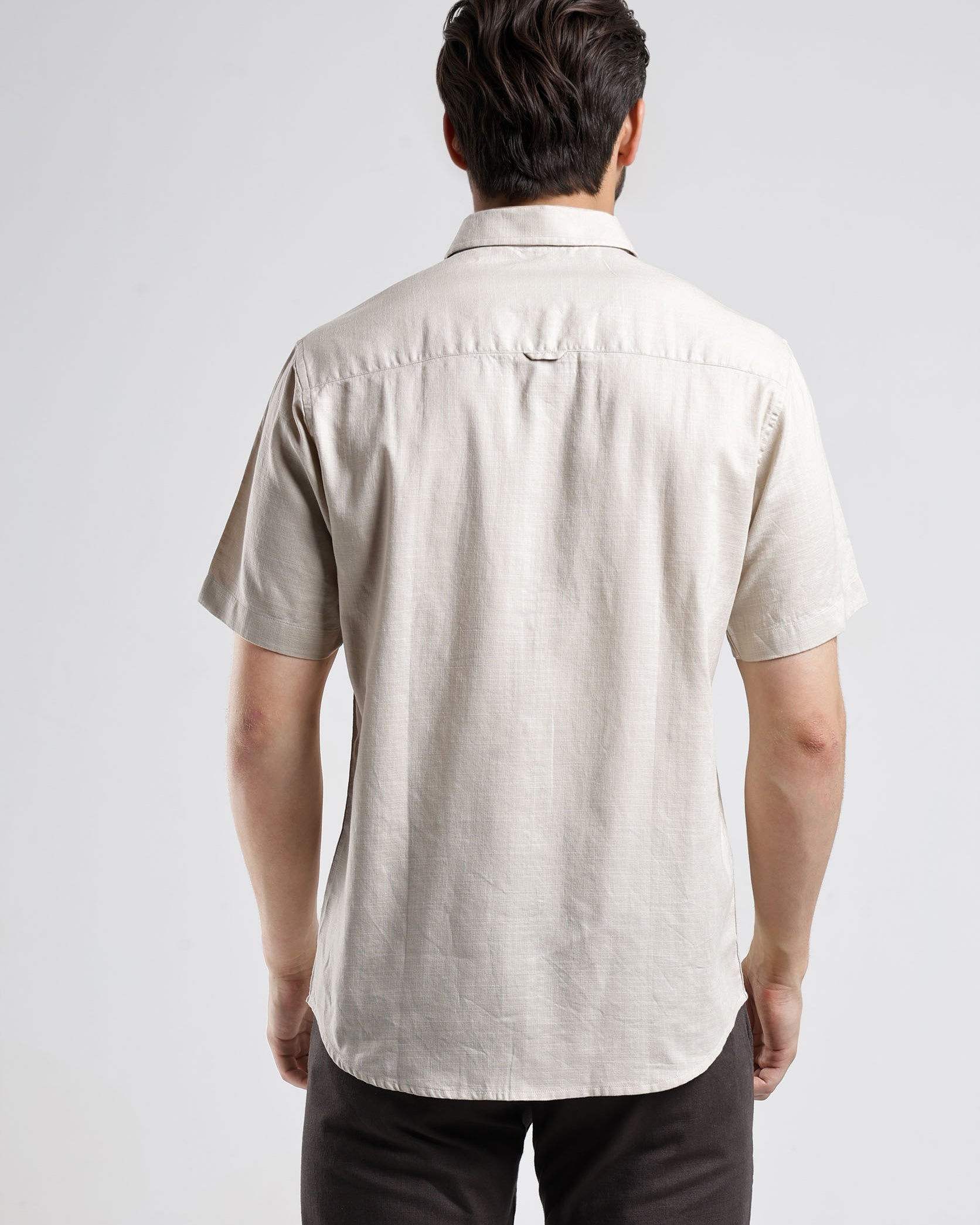 Man wearing a beige short-sleeve shirt on a white background