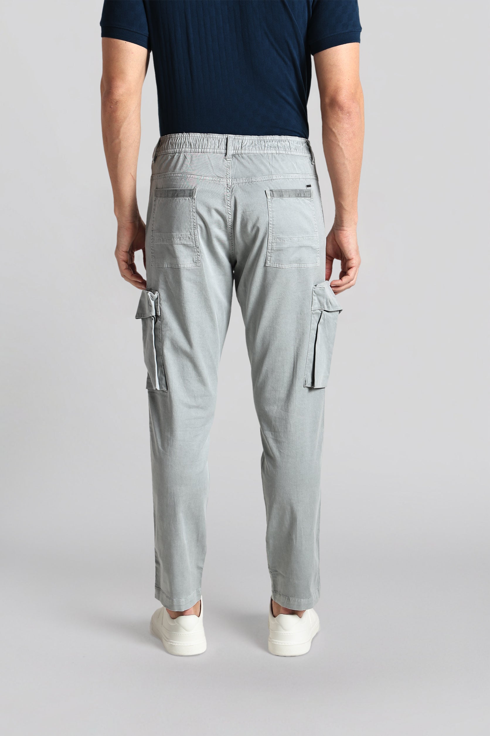 Person wearing light gray cargo pants on a plain background