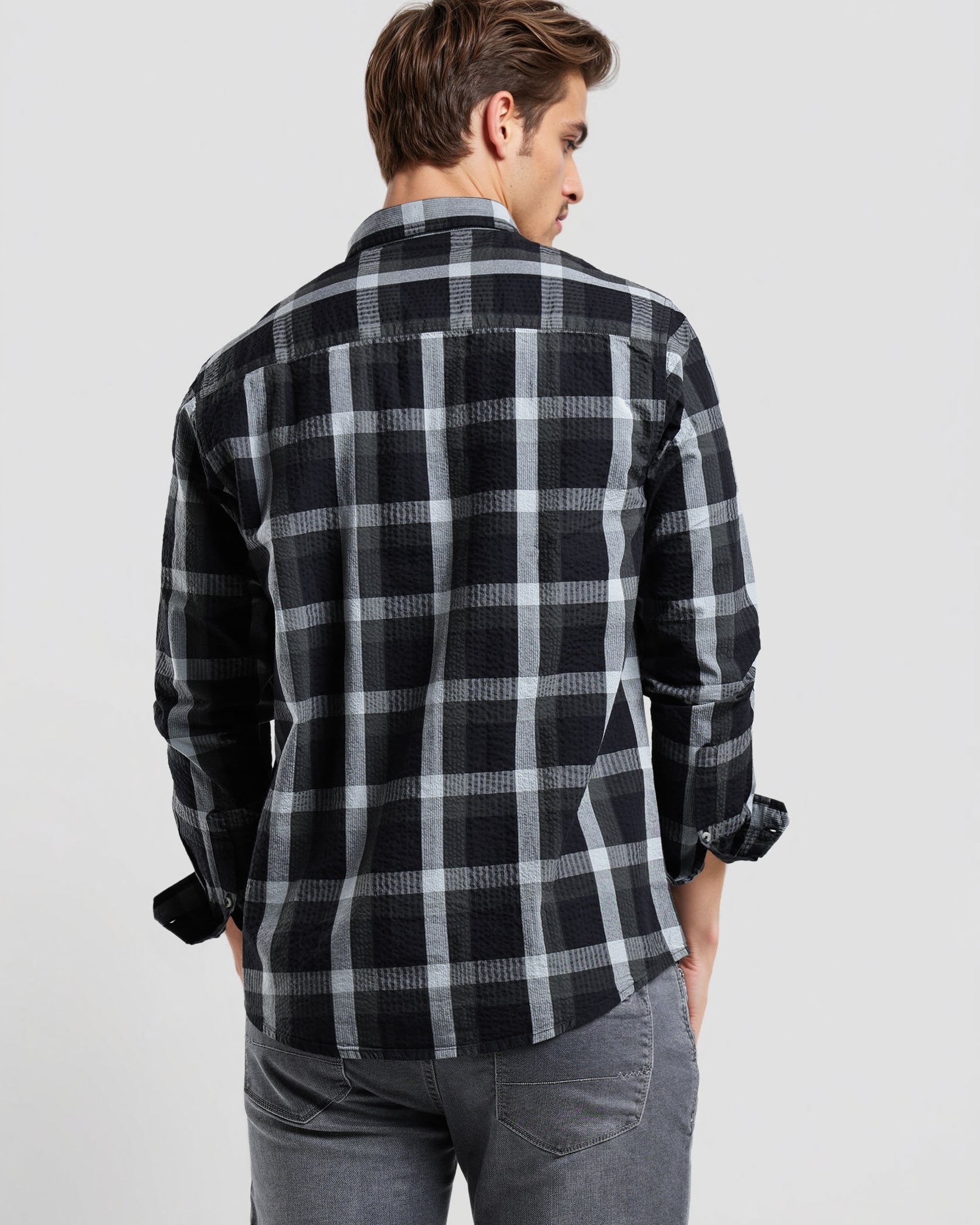 Man wearing a black and gray plaid shirt on a light gray background