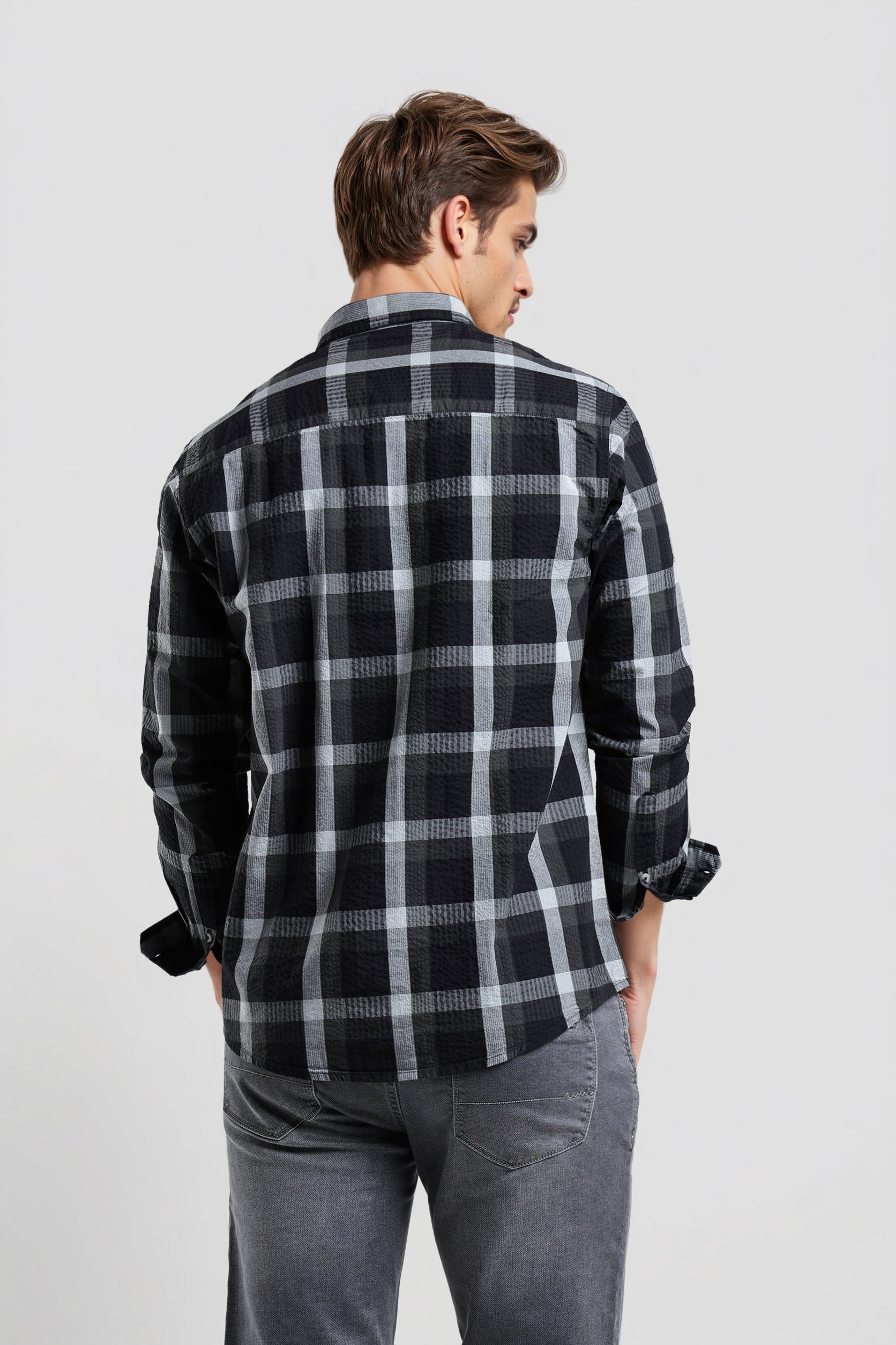 Man wearing a black and gray plaid shirt on a light gray background