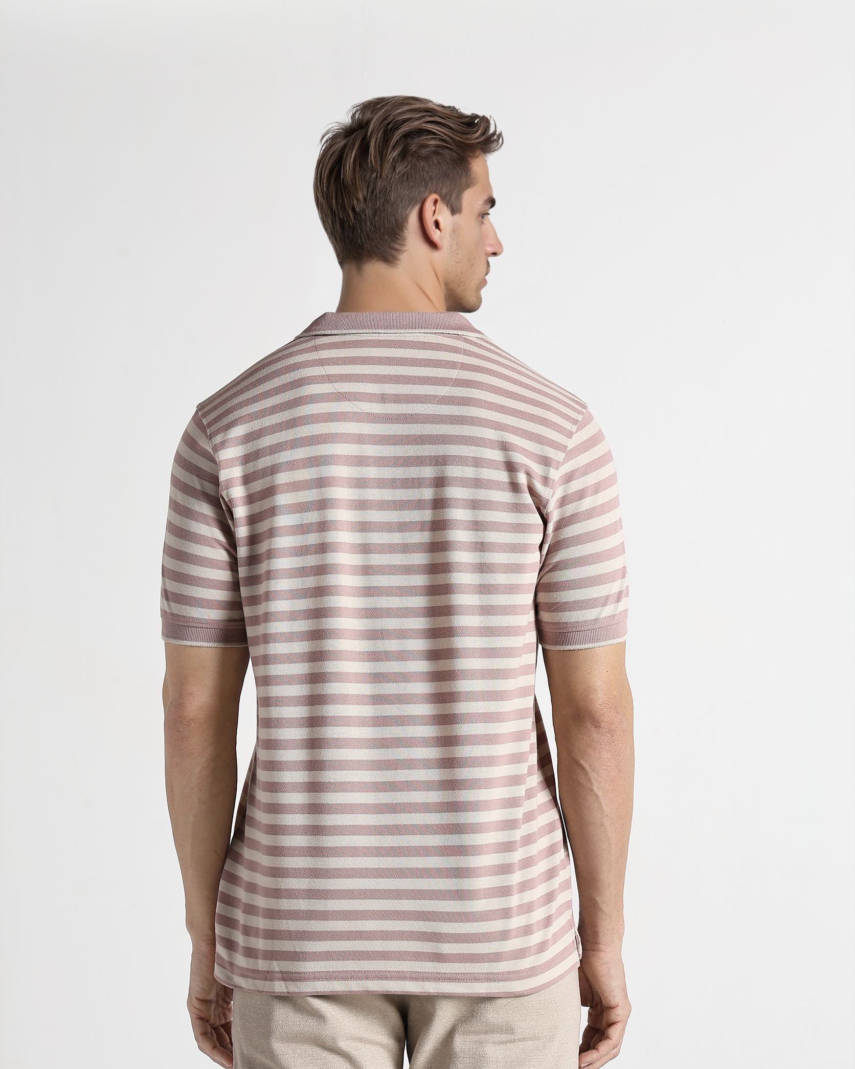 Man wearing a striped shirt and beige pants on a white background