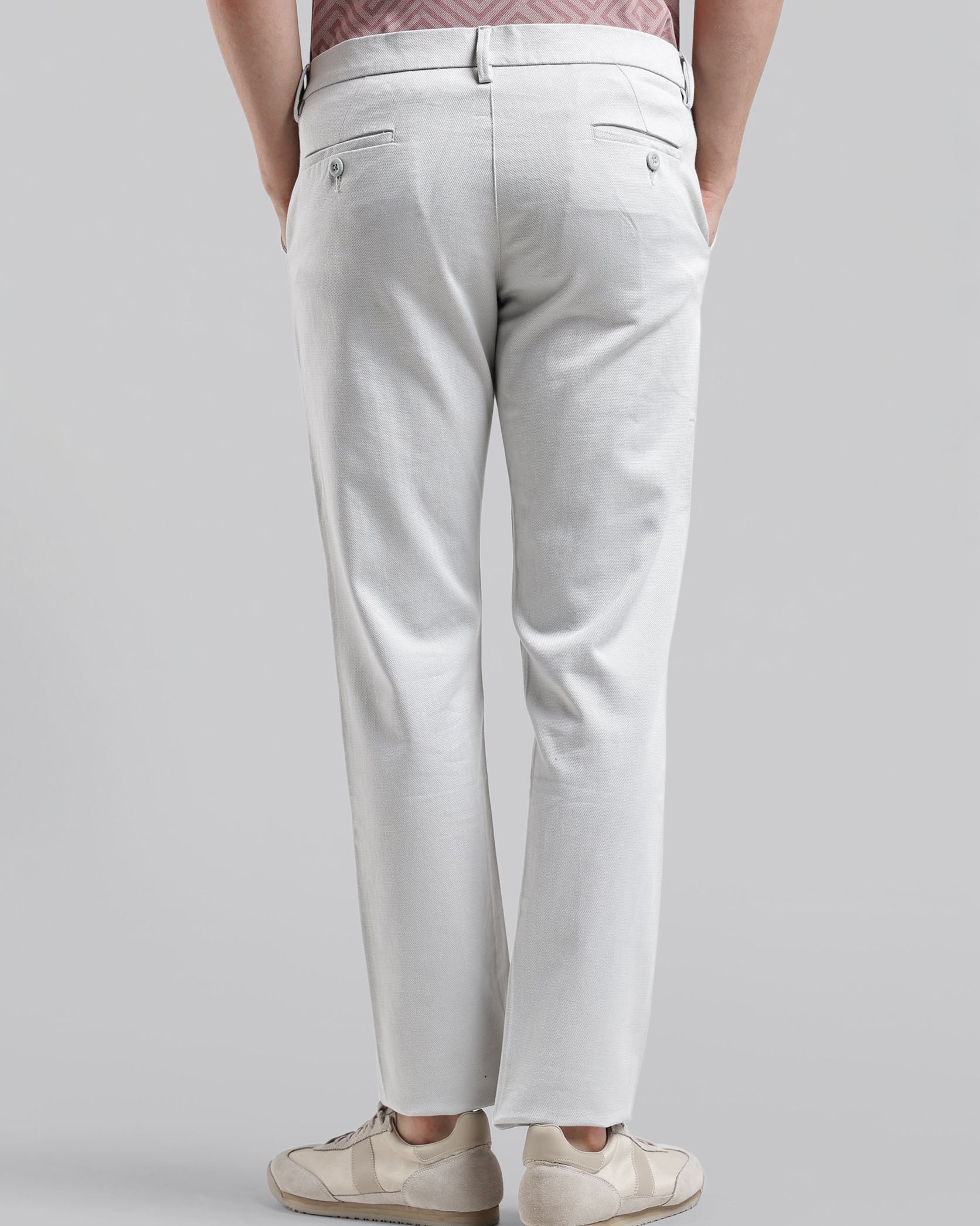 Person wearing light gray pants on a plain background