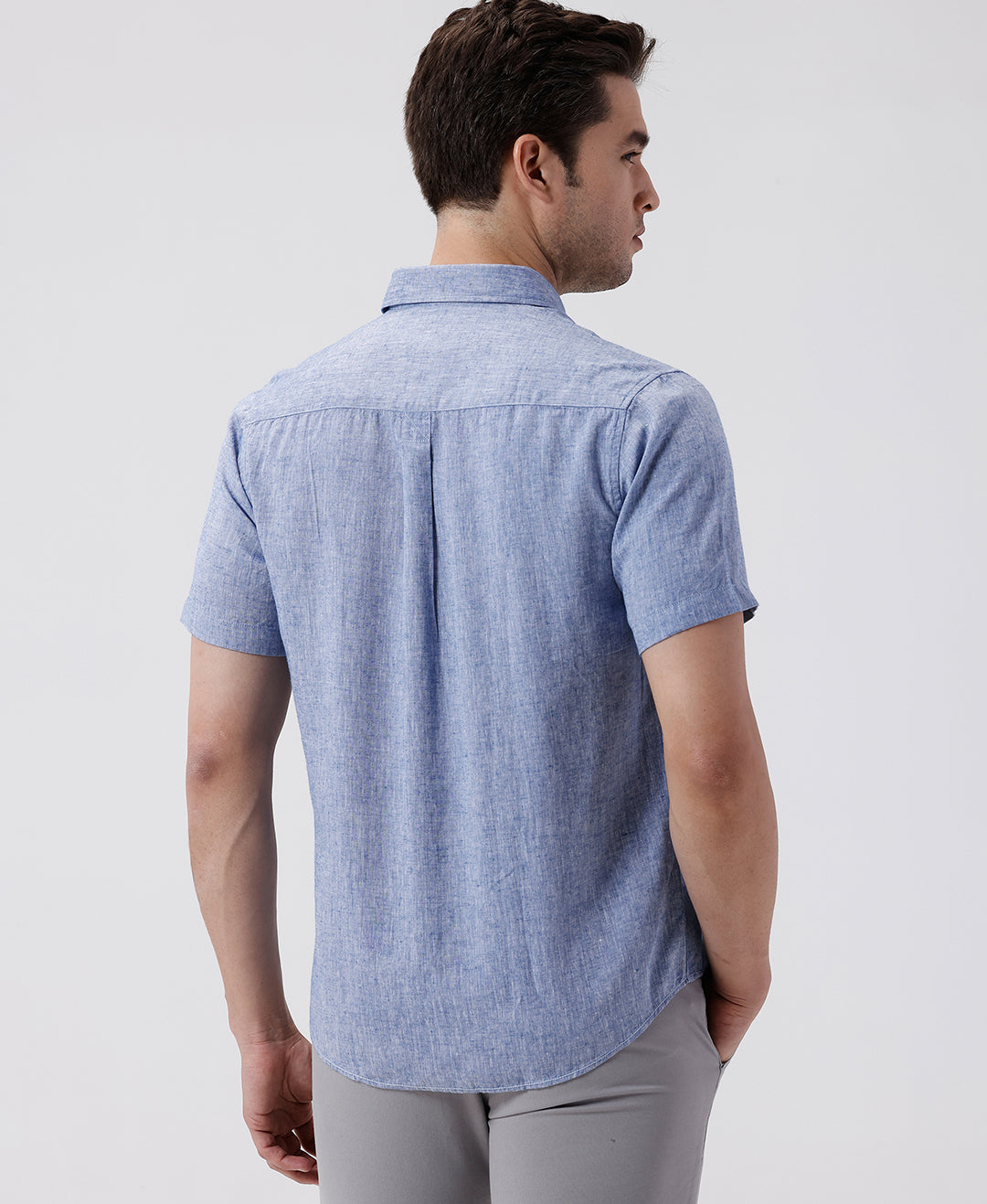 Man wearing a blue premium tensil linen shirt blue on a light gray background