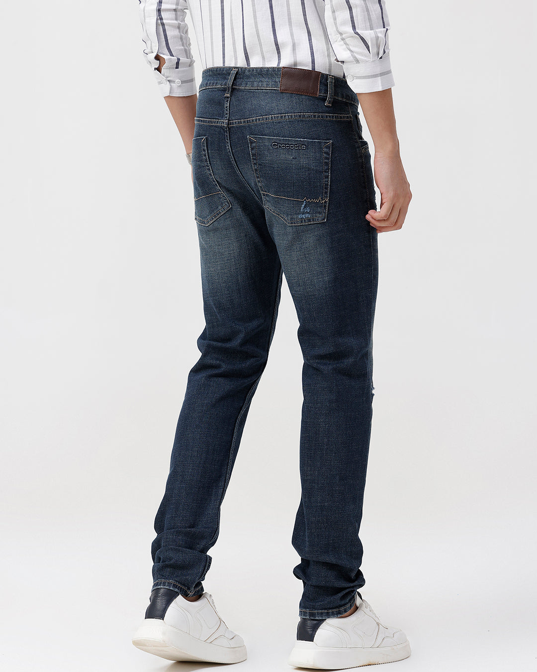 Person wearing dark blue jeans and a plaid shirt on a white background