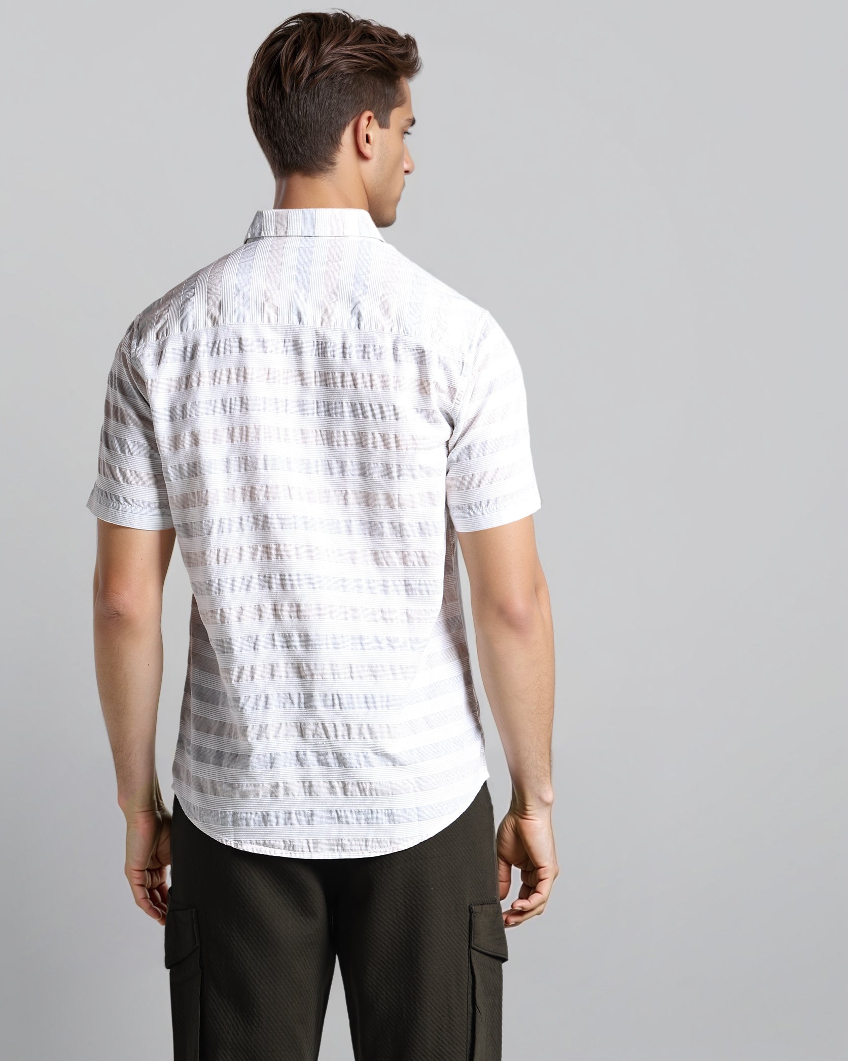 Man wearing a white patterned shirt and black pants on a gray background