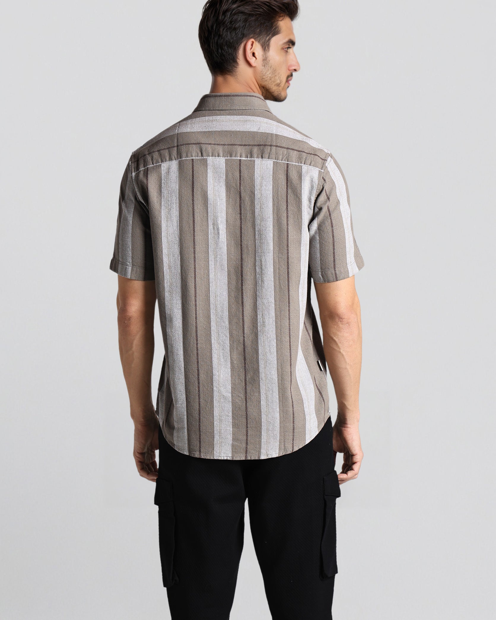 Man wearing a striped shirt and black pants on a light gray background